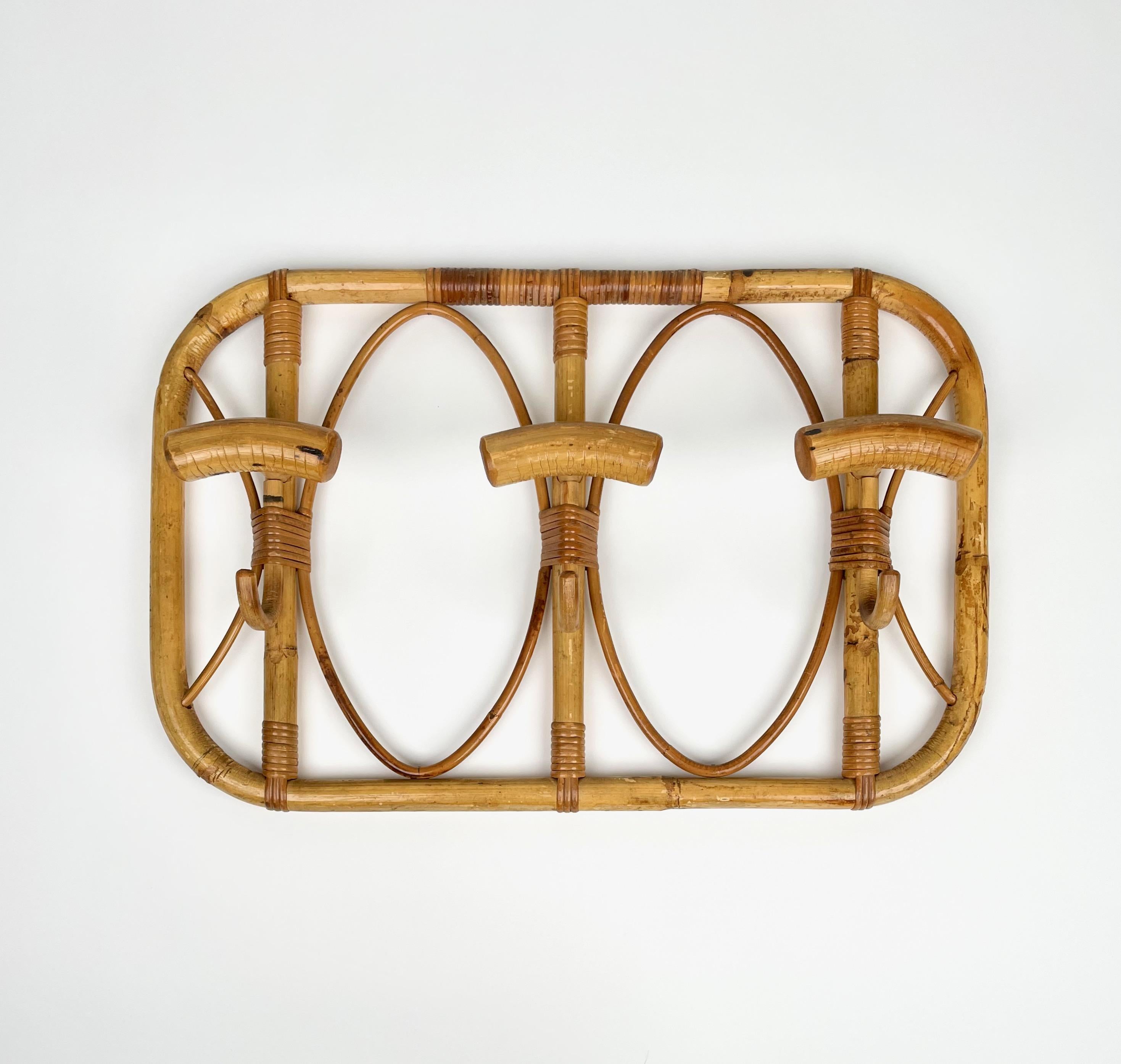 Rectangular coat hanger with rounded corners in bamboo and rattan featuring three hooks. 

Made in Italy in the 1960s.