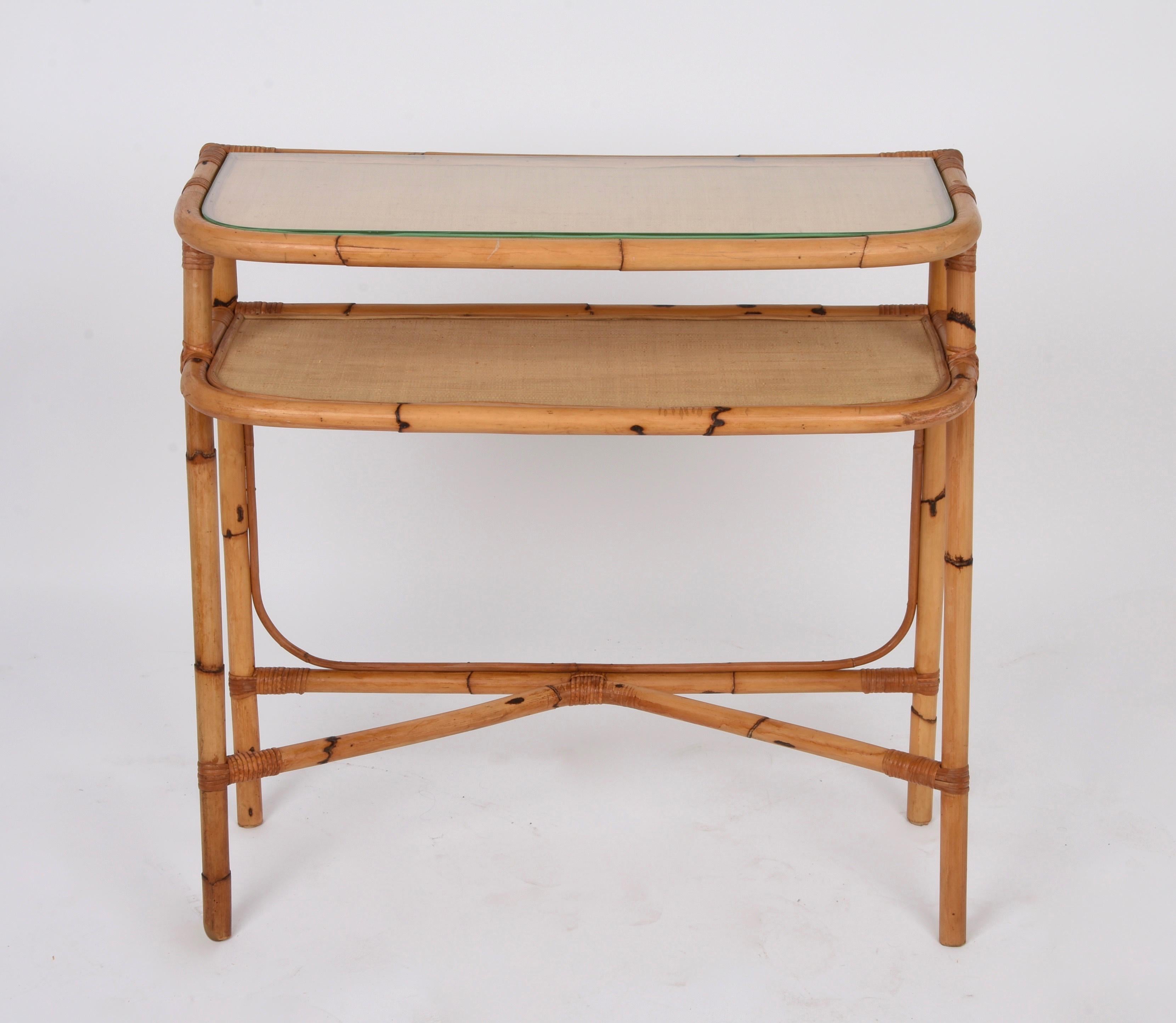 Showy console in bamboo and rattan with two shelves, with the top one in glass. This piece was produced following the style of Franco Albini in Italy in the 1970s.

This console rests on four bamboo legs joined together by a stretcher and two