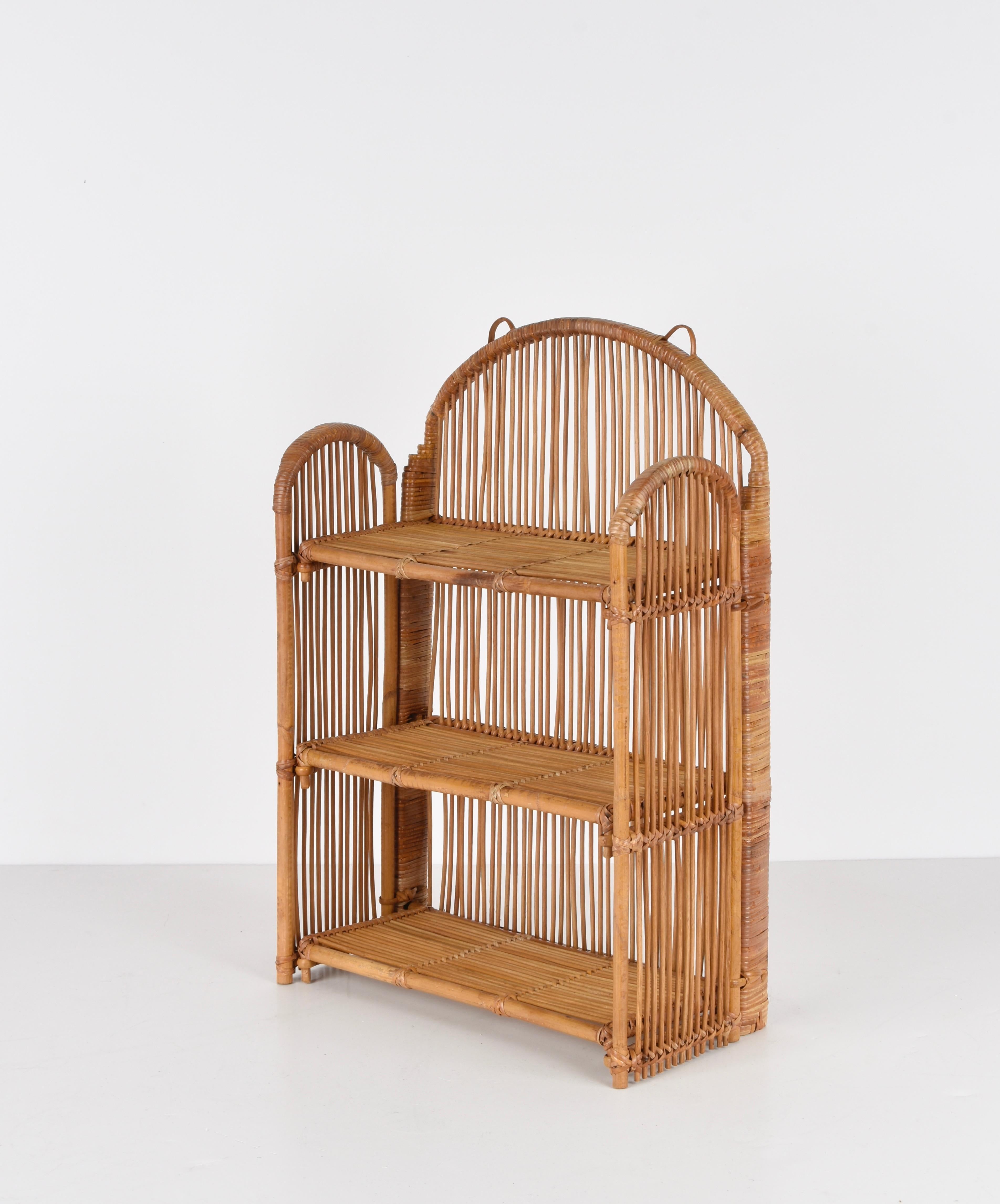 Stunning midcentury bamboo and rattan shelf or storage display built on three levels. This fantastic piece was produced in Italy during the 1980s.

This elegant item is unique as it has three rattan shelves and a structure that can be fully folded