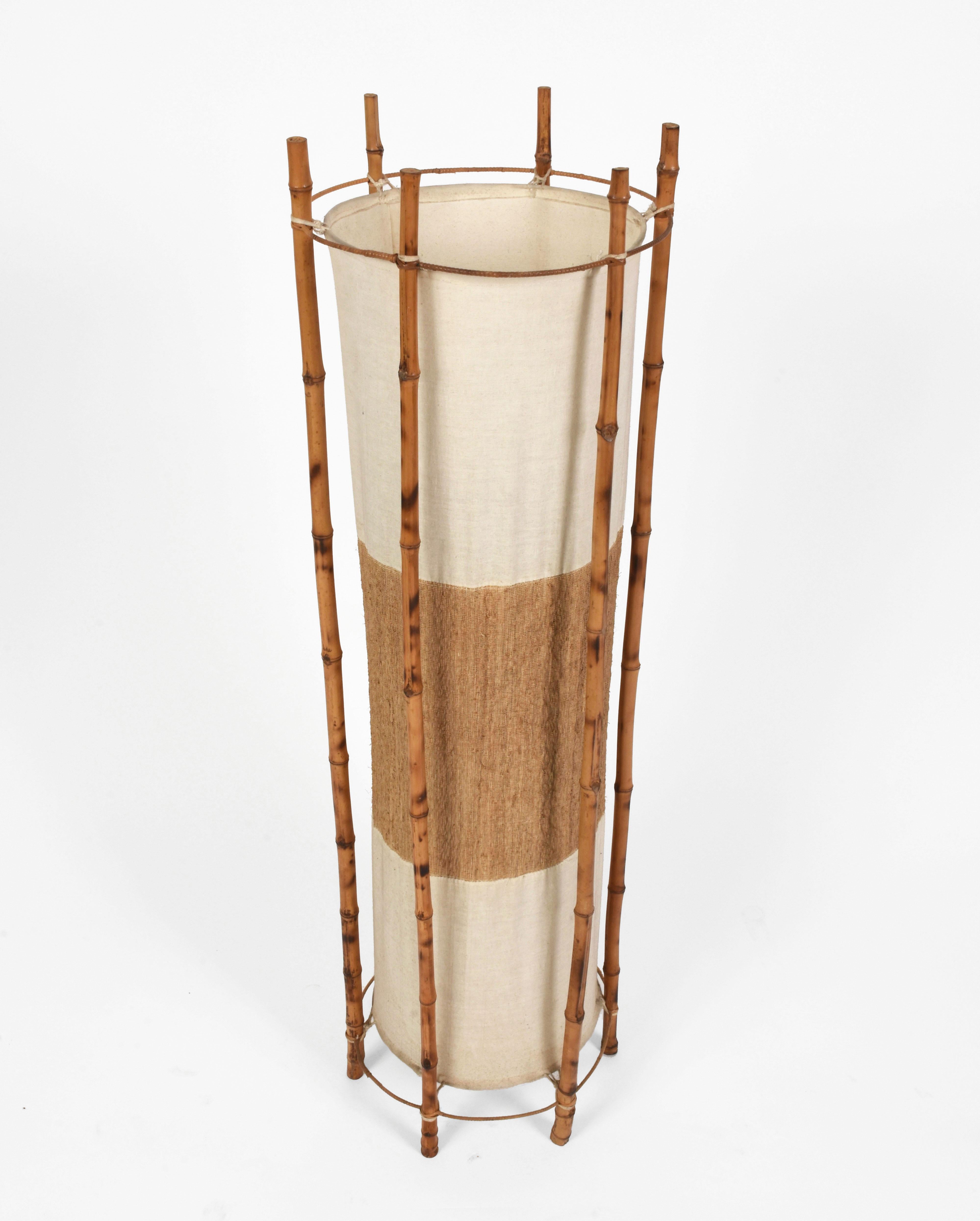 Wonderful bamboo and rattan midcentury floor lamp. This marvelous piece was produced in Italy during 1960s in the style of Louis Sognot.

The external structure is made of bamboo and rattan and holds two cones narrowing in the centre. The effect