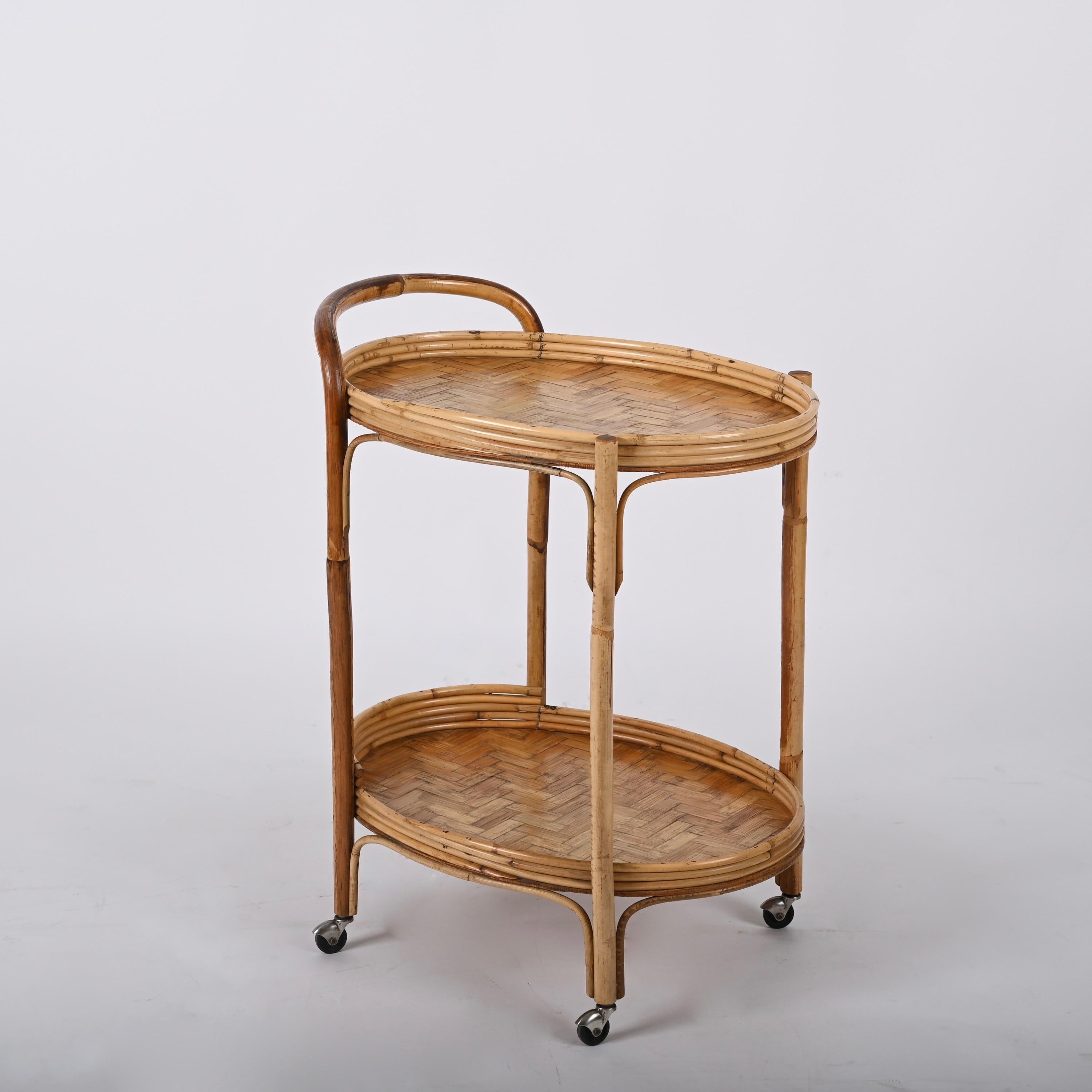 Midcentury rattan and bamboo cane oval bar cart with four wheels. This fantastic piece was designed in Italy during the 1960s.

A wonderful item in fantastic vintage condition, with four small wheels and two oval shelves made of rattan with a bamboo