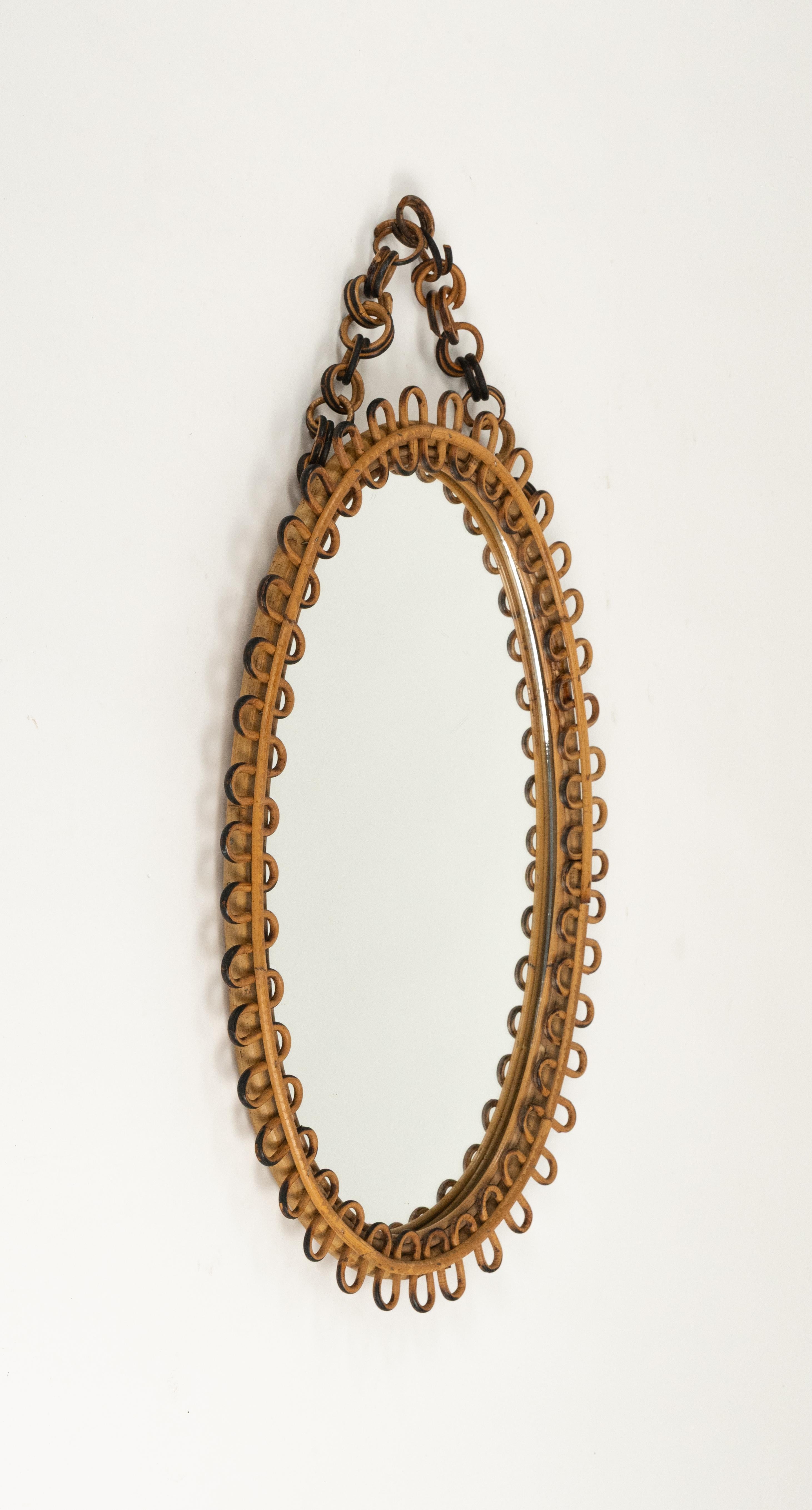 Midcentury beautiful oval wall mirror with chain in bamboo and rattan in the style of Franco Albini.

Made in Italy in the 1960s.   

A highly decorative mirror.   

Dimensions without chain:  
Height 66 cm.  
Width 44.5 cm.  
Depth 3.5 cm.