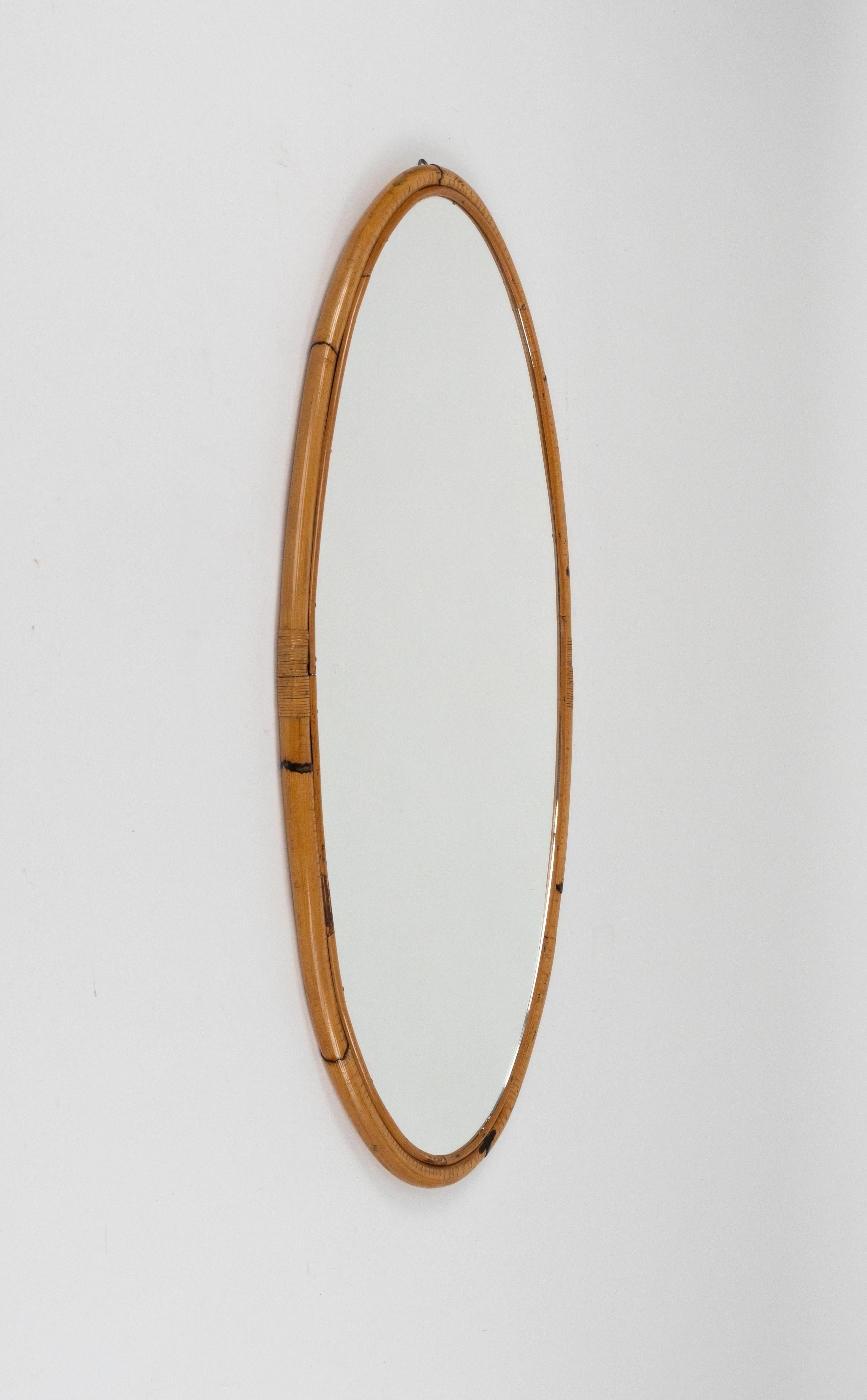 Miroir mural ovale en rotin et bambou.

Fabriqué en Italie dans les années 1970.

Ce miroir est idéal pour une chambre à coucher, un dressing, un vestiaire ou un hall d'entrée.
