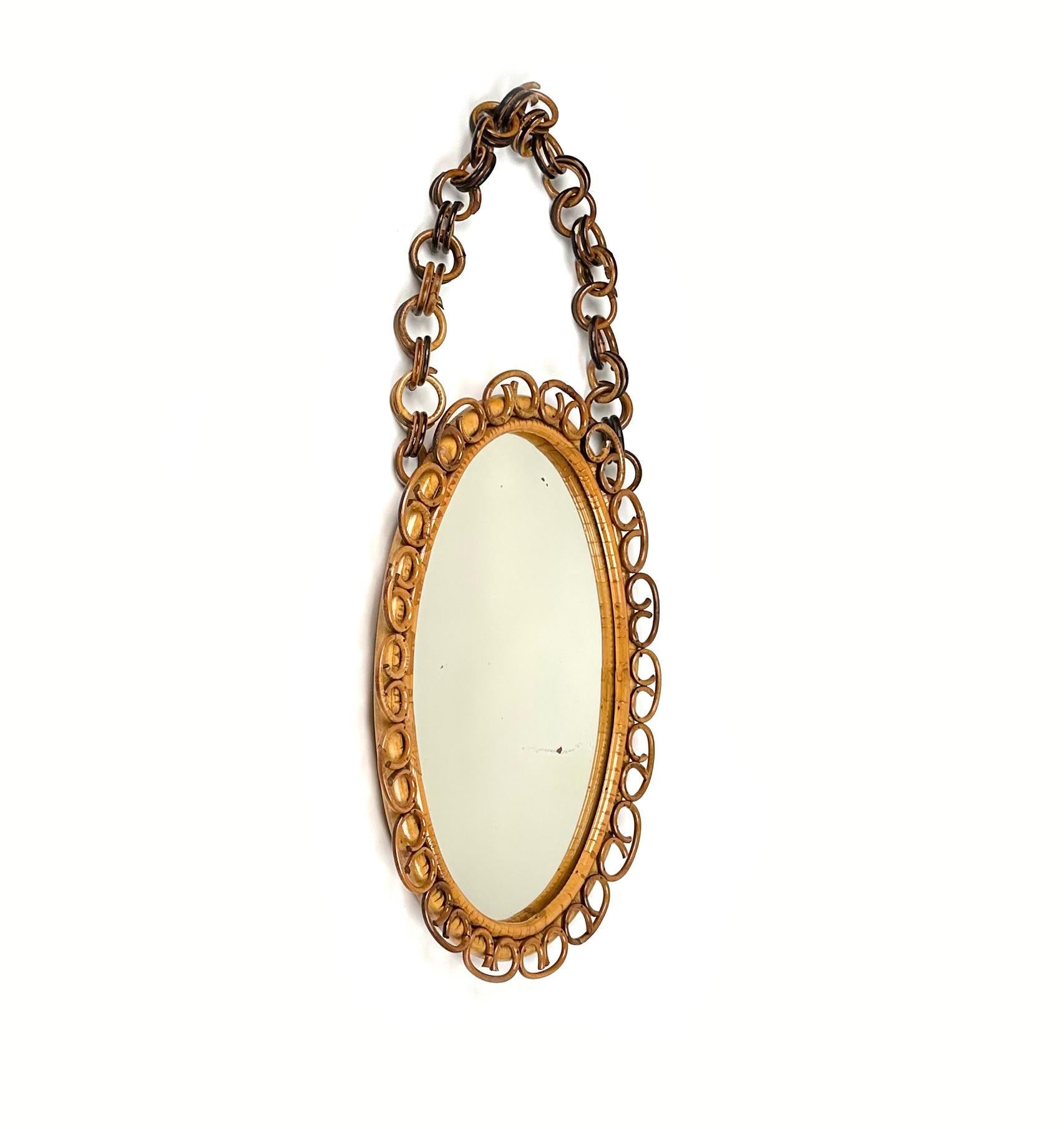 Midcentury Beautiful oval wall mirror in bamboo and rattan with chain.

Made in Italy in the 1960s.

Bamboo / rattan has been polished by a professional restorer.

the mirror, original of the period, shows signs of discolouration.

A highly