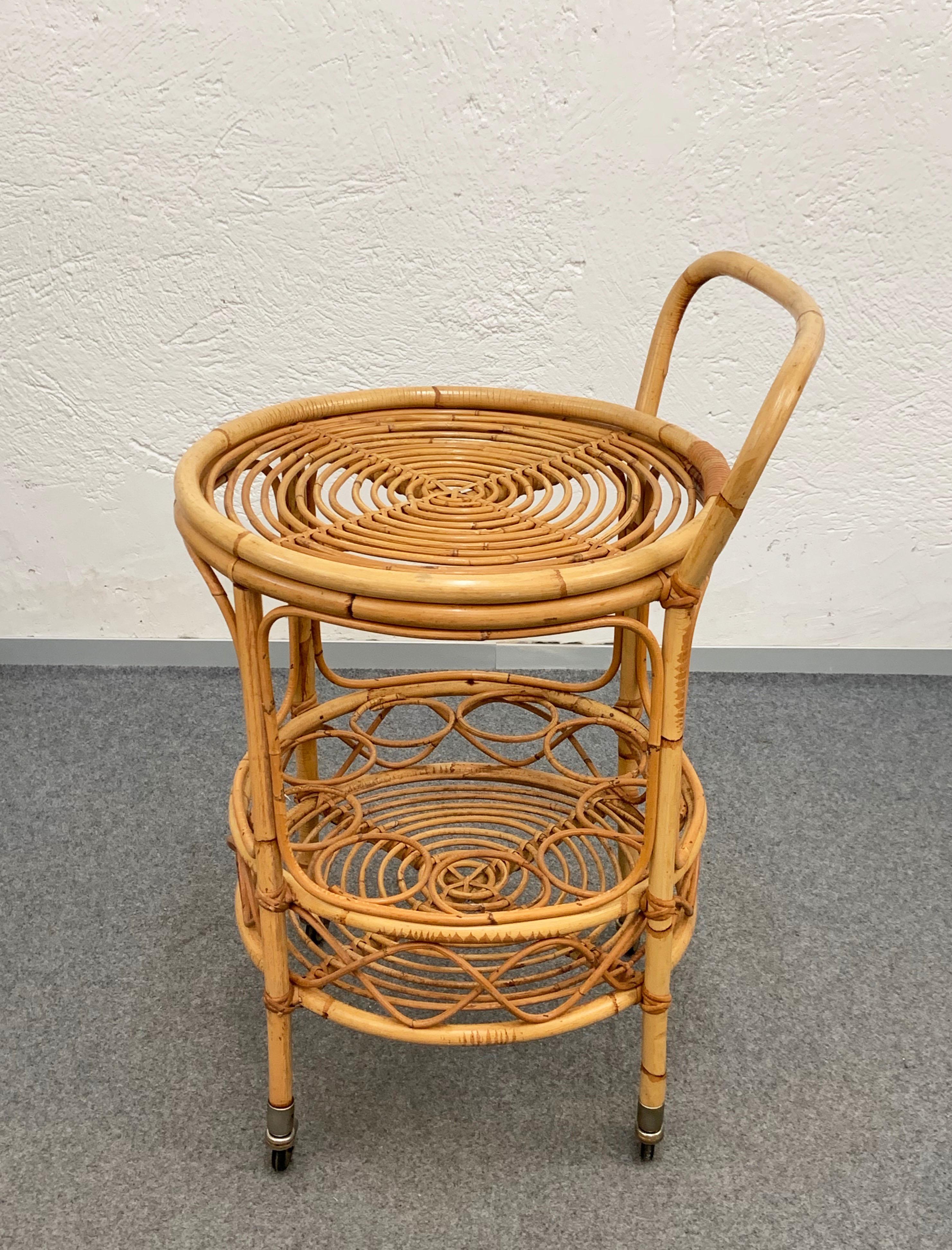 Fabulous midcentury bamboo and rattan bar cart in perfect conditions. This item was produced in Italy during 1960s.

It is made in bamboo with rattan finishes, it has two levels and four small wheels at the bottom. The lower level has a bottle