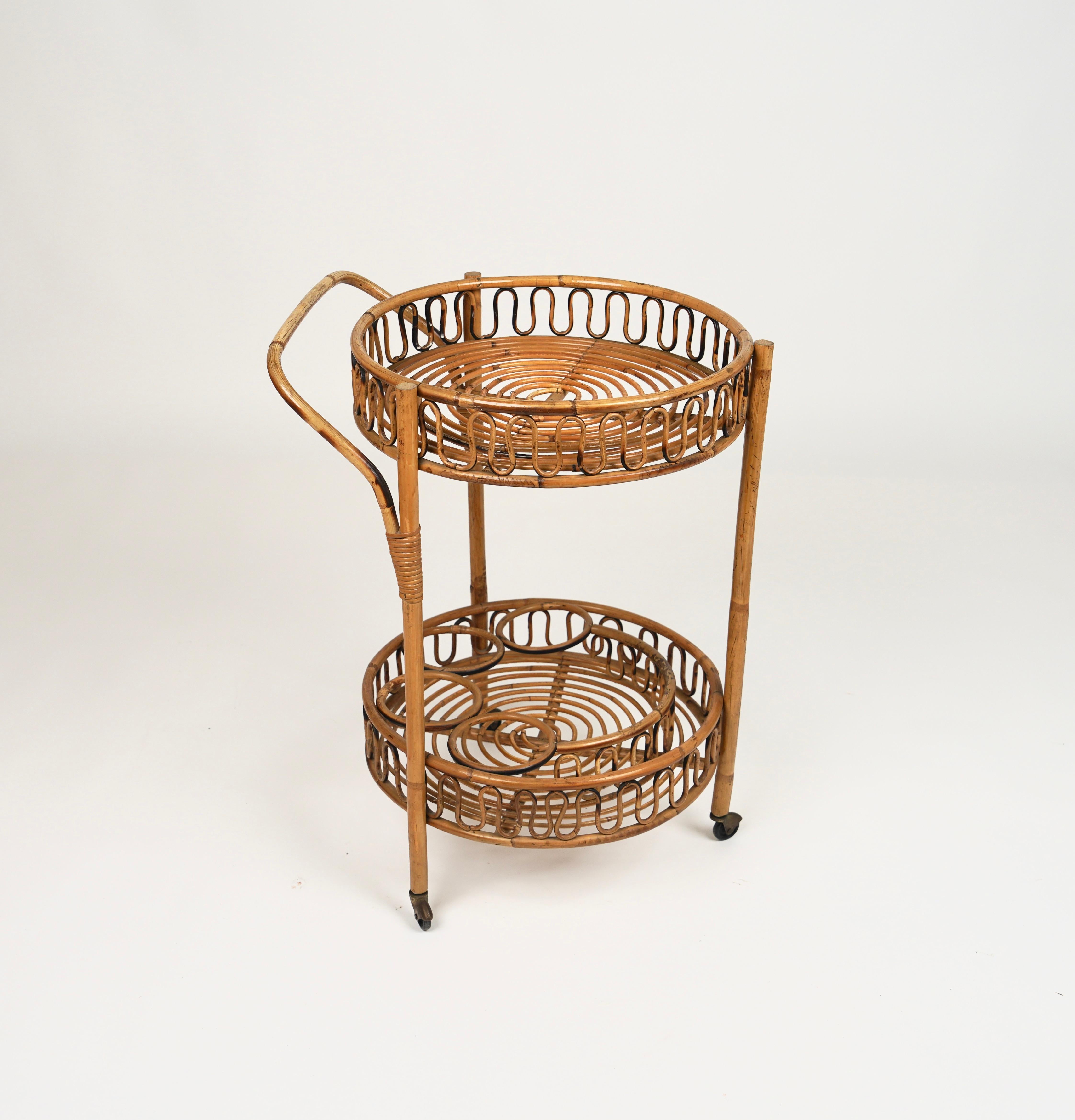 Midcentury round serving bar cart in bamboo and rattan featuring with four bottle holders and a handle on the top level.
Made in Italy in the 1960s.
A fabulous serving table that will be the centrepiece of a midcentury bar or living room.
