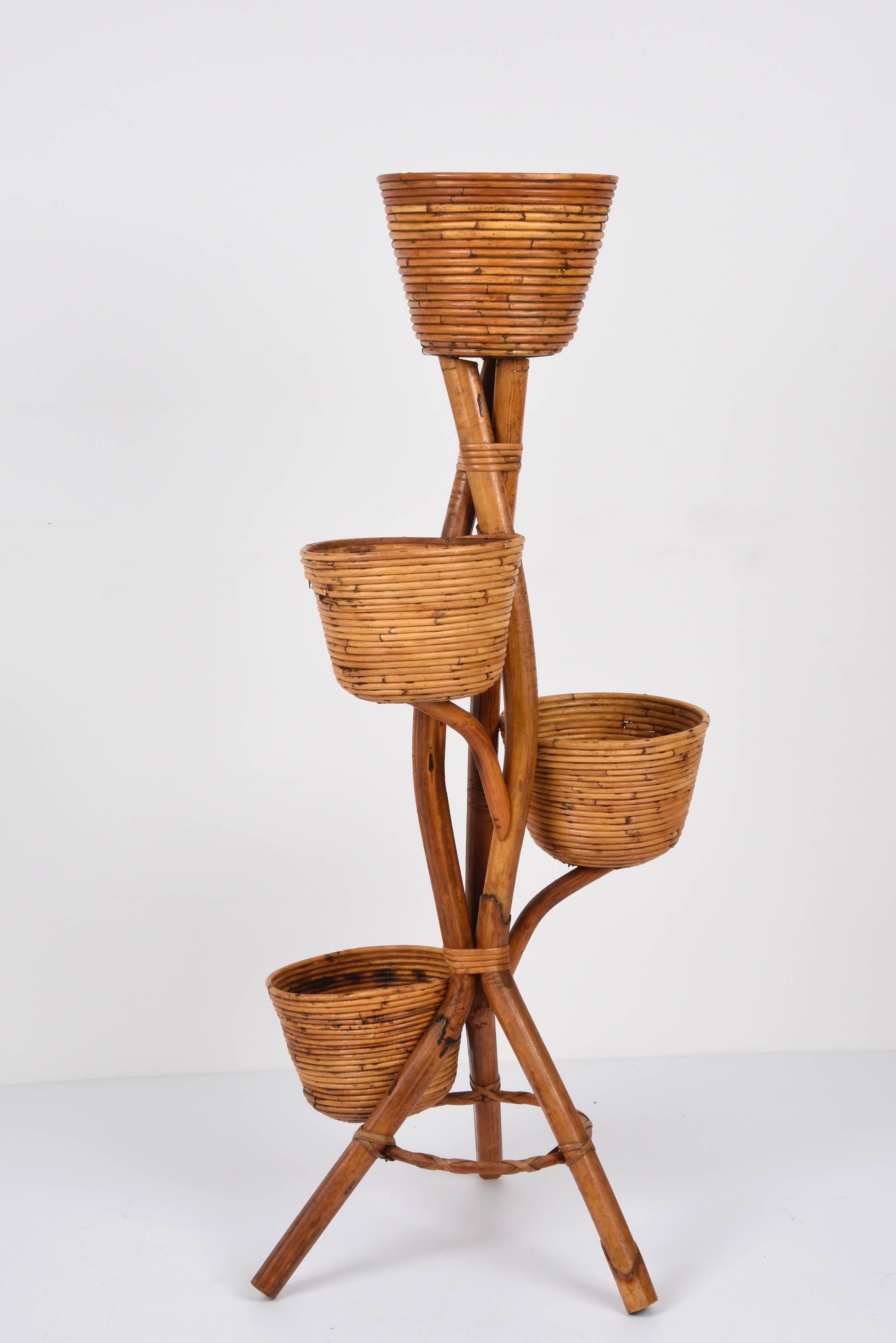 Amazing midcentury flowers or plant holder in bamboo and wicker. This fantastic item was designed in Italy during the 1950s.

This magnificent piece has a sinuous bamboo structure with a tripod base, while the fantastic plant holders are made of