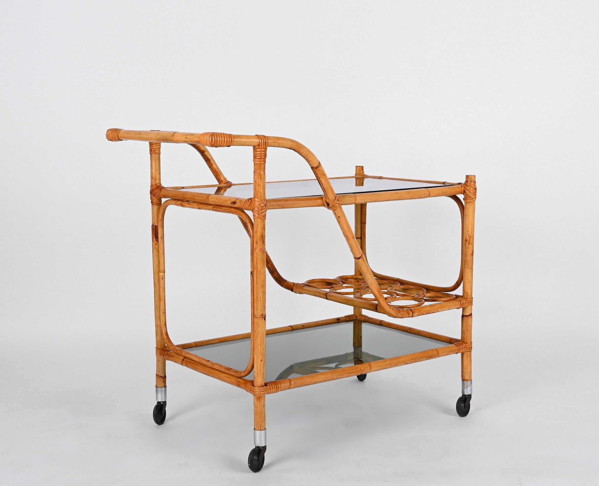 Gorgeous mid-century rectangular bamboo cane and rattan bar cart with two smoked glass shelves and metal wheels. This unique piece was produced in Italy during the 1960s.

A wonderful piece in fantastic vintage condition, with eight bottle holders
