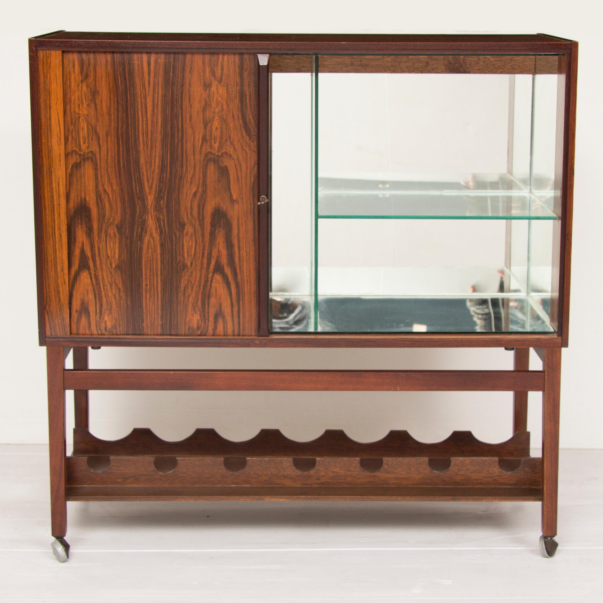 Midcentury rosewood bar cart.
Beautiful rosewood cocktail cabinet with tabour door revealing mirrored interior, fitted below for bottle storage.
Danish, circa 1960
Measures: 85 cm H, 84.5 cm W, 34.5 cm D.