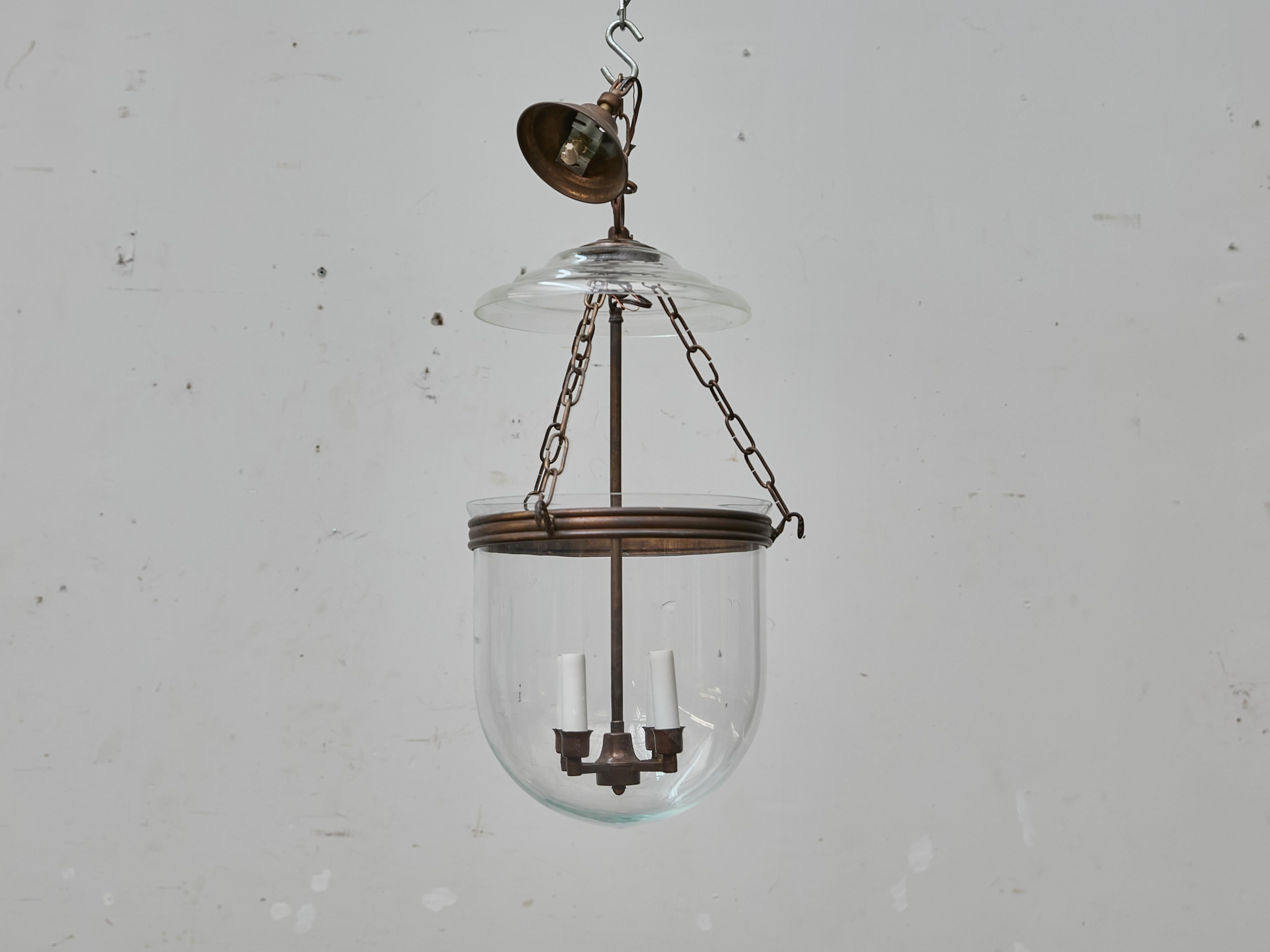Questa lanterna a campana di metà secolo offre una rivisitazione raffinata di una forma tradizionale, fondendo proporzioni classiche con una sottile modernità. La cupola in vetro trasparente soffiato a mano, che termina dolcemente in una base