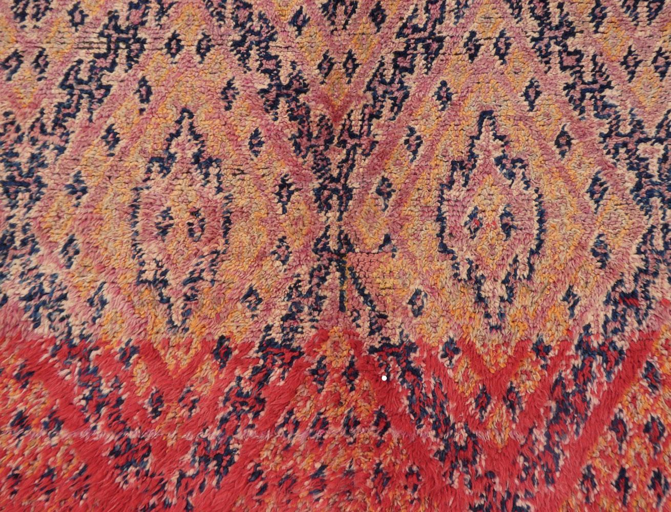 Tappeto Beni Mguild marocchino del 1970 circa, tessuto a mano con lana color albicocca, indaco, lavanda e rosso con un elaborato disegno di simboli berberi.
I tappeti Beni Mguild hanno un tipico aspetto arcaico e una miscela di colori tono su tono