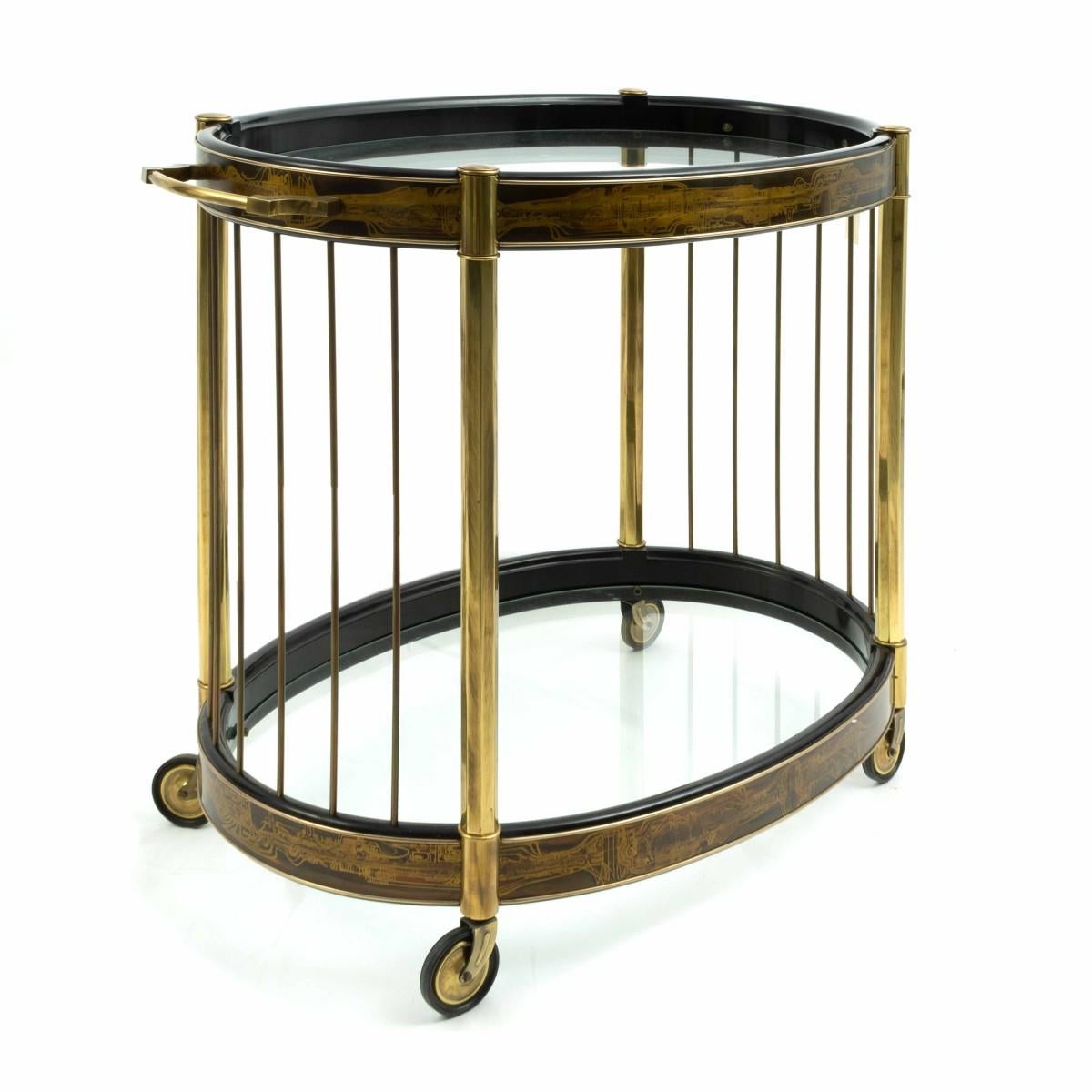 Mid-Century Modern Bernhard Rohne two-tier brass serving / bar cart made by Mastercraft with acid etched details and black lacquered wood with oval glass surfaces.
 