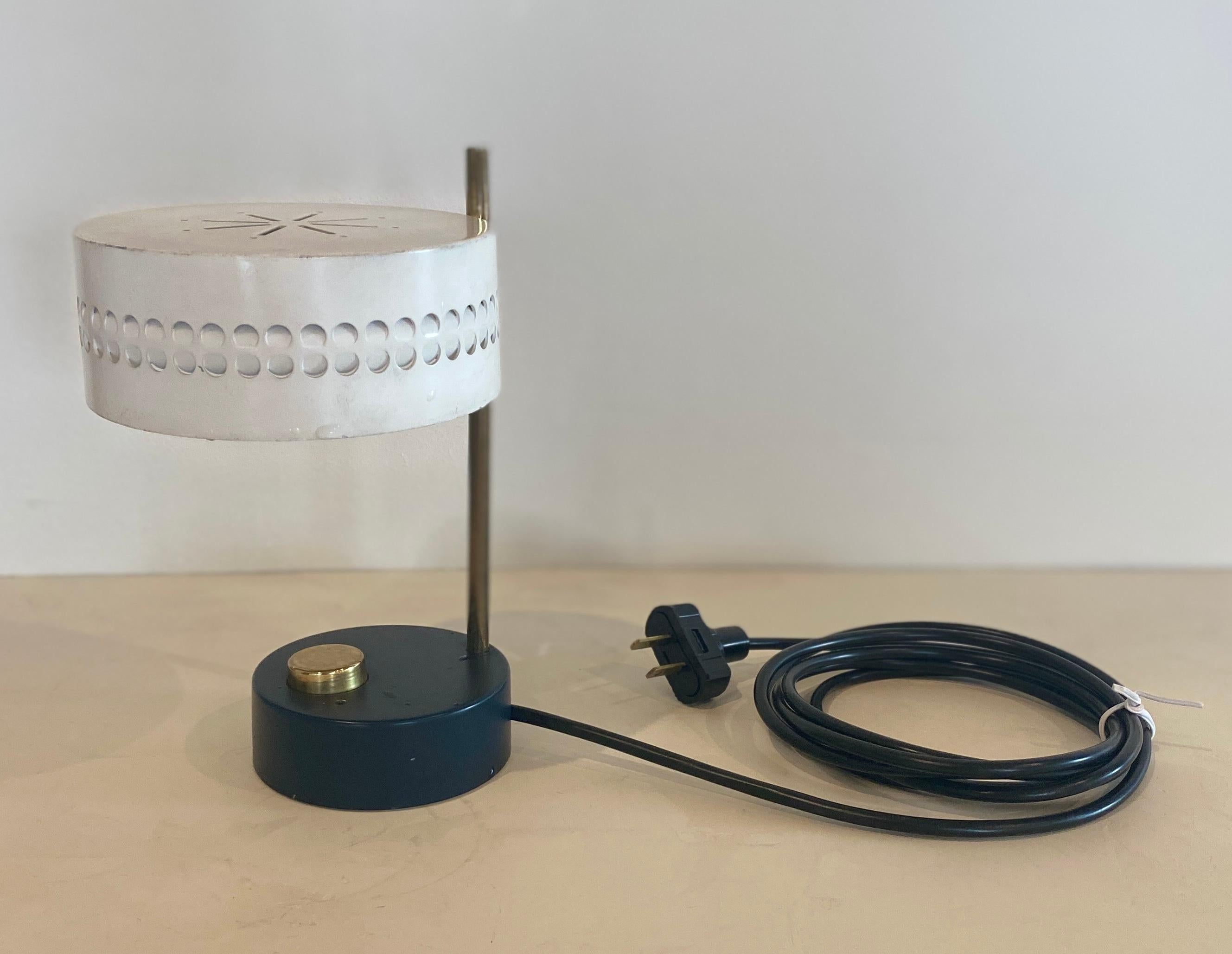 Small table lamp by Mathieu Matégot, circa 1950-1959 with an oversize white perforated metal shade and a black base, complimented by an oversized brass switch and brass rod. Newly rewired for USA. Images with black cord are the new rewiring. 