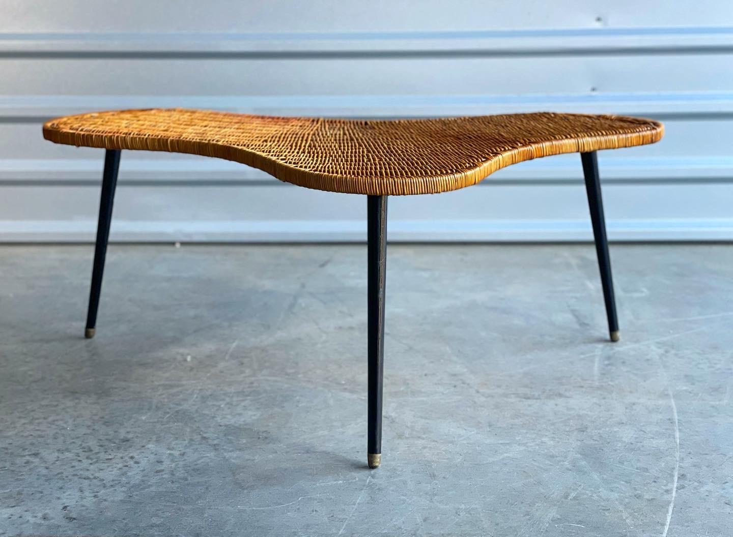 Rare organic rattan and lacquered iron coffee table, France, circa early 1950's. Free flowing kidney shaped woven top with tapered metal legs. 
Table is in overall excellent condition. Rattan is completely intact and shows a gorgeous warm patina.