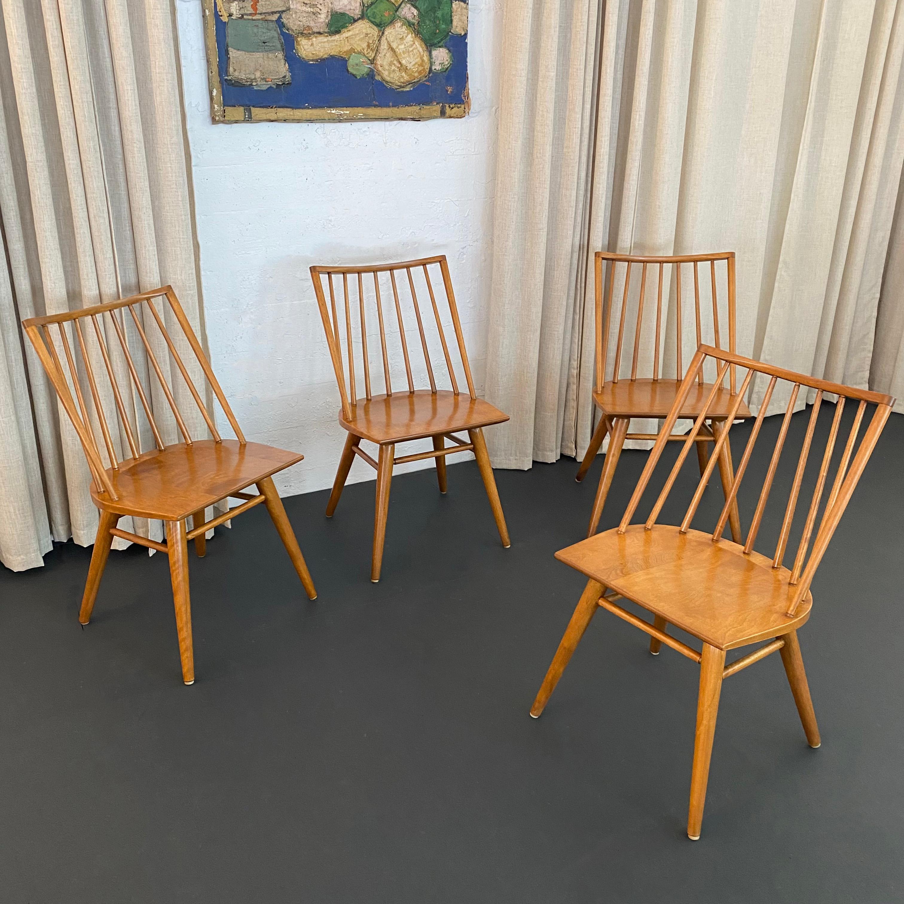 This set of four model 7408 birch spindle back dining chairs were designed by Leslie Diamond for Conant Ball Furniture's Modernmates line, circa 1956. Because the Modernmates line was designed by both Leslie Ball and Russel Wright these chairs have