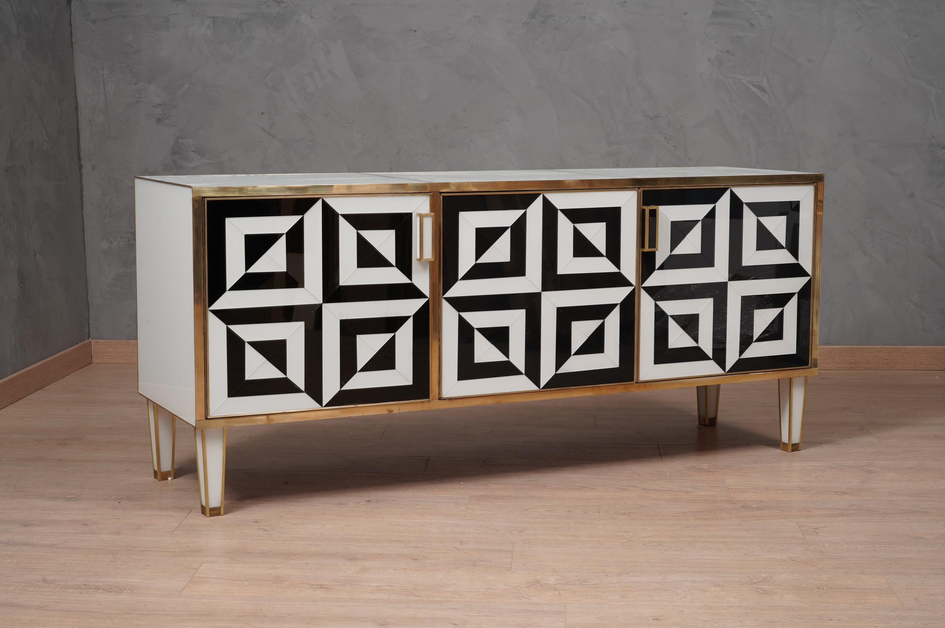Italian-style sideboard entirely in black and white glass; fronts of the doors with play of color of the glasses.

The sideboard has a wooden structure with three beautiful very wide doors. The structure was completely covered in white glass and