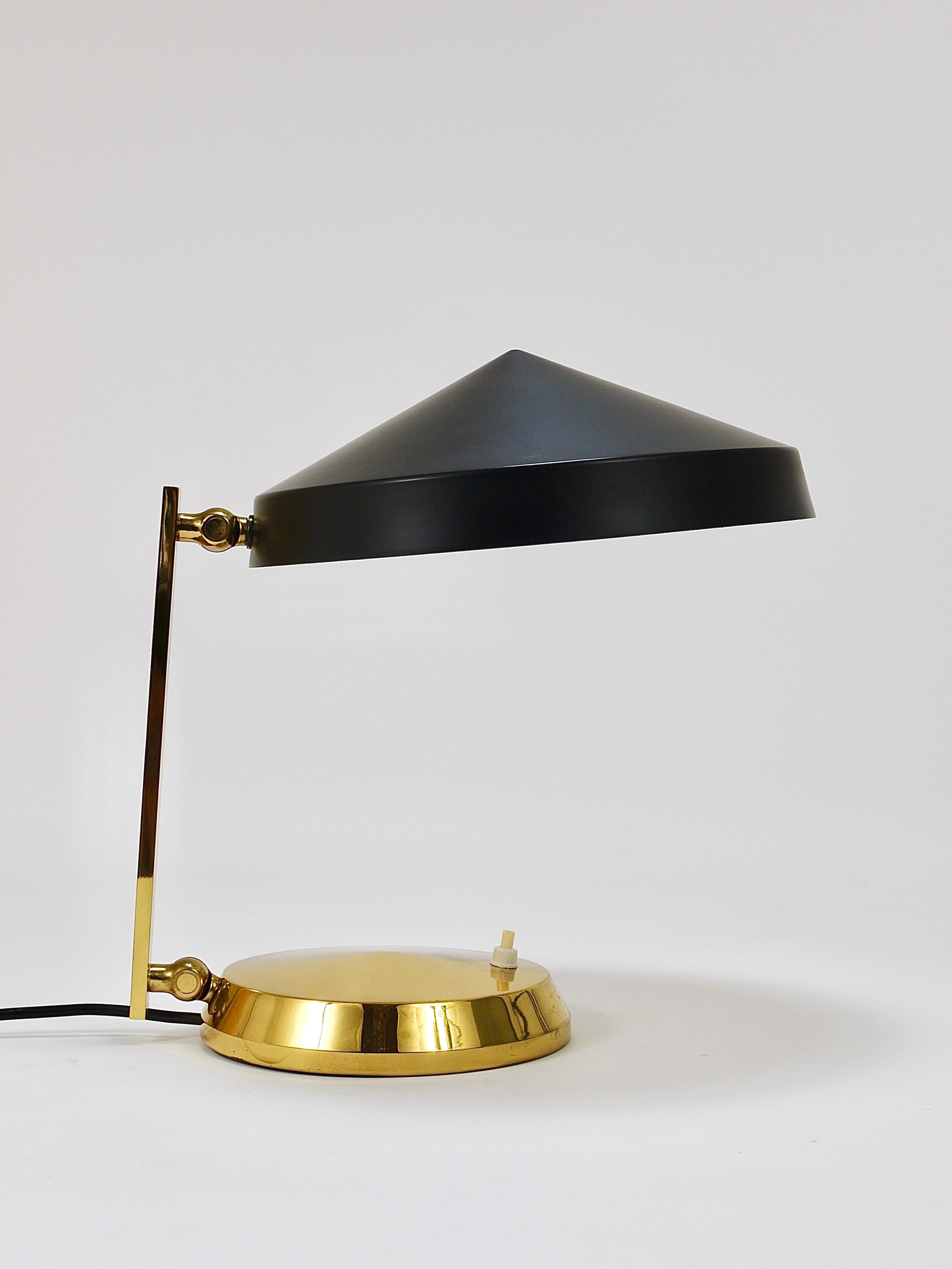 A beautiful Mid-Century table or desk lamp from the 1960s, made in Austria. This charming light a brass base with an adjustable neck and a wonderful black conical aluminum lampshade with white interior. In good condition with nice patina. In the