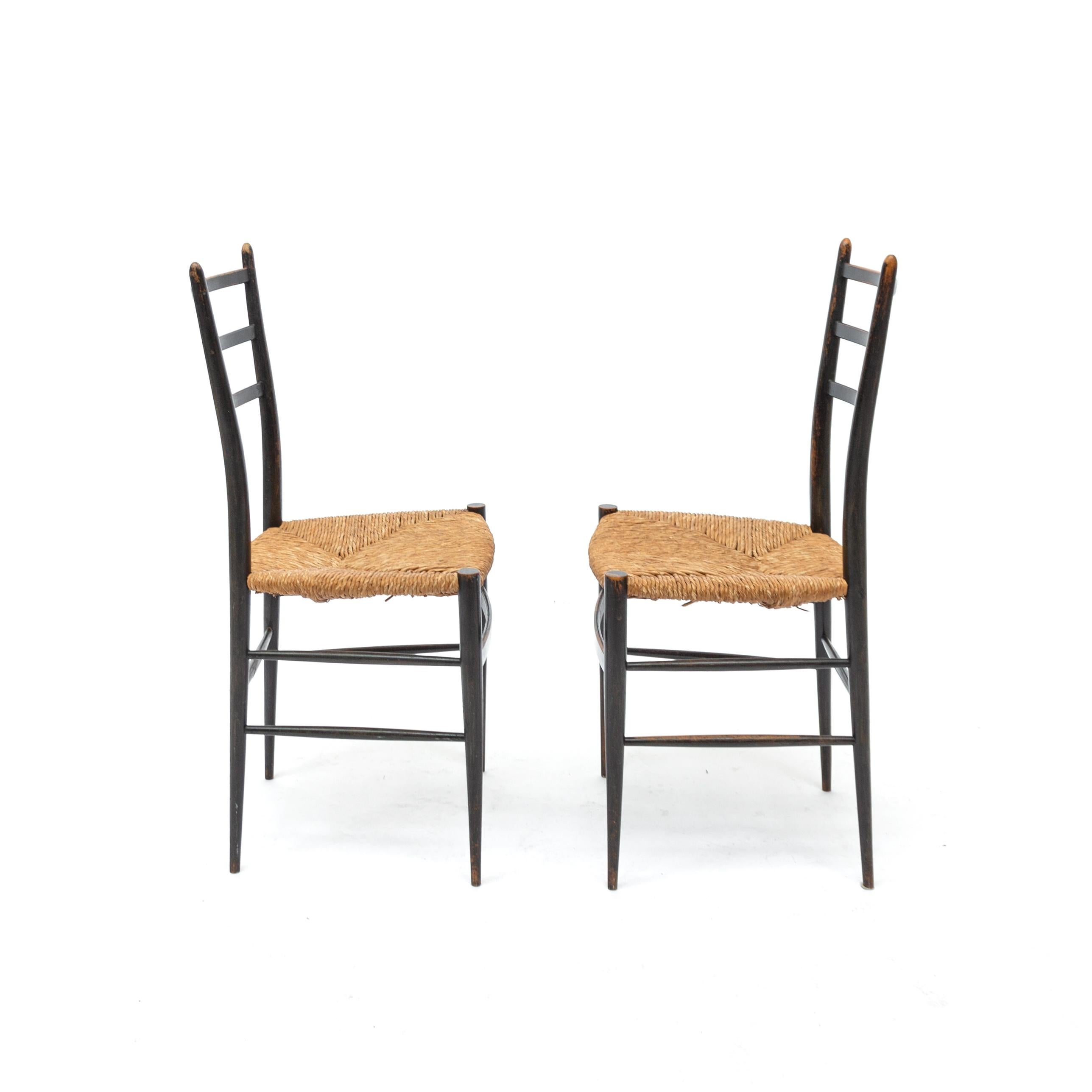 Priced as set of 2. Famous Italian chairs from the 1950s in Gio Ponti style. Black lacquered solid wood structure. Seats in natural fiber.