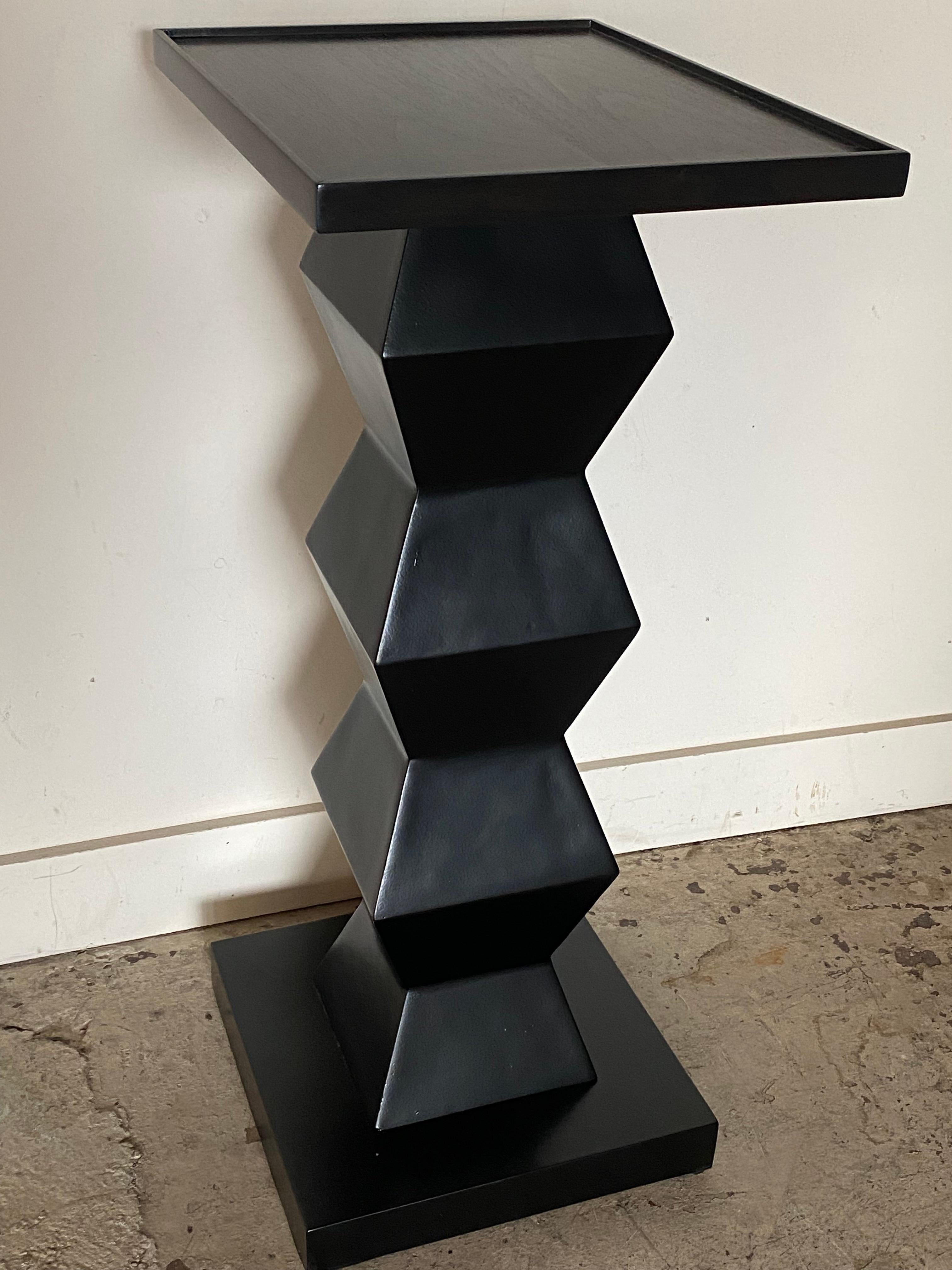 This pedestal rests on a black satin finish hexagonal baluster column. The top is surrounded by a little flange.
It can be used as a pedestal in the middle of the room or as a little console.