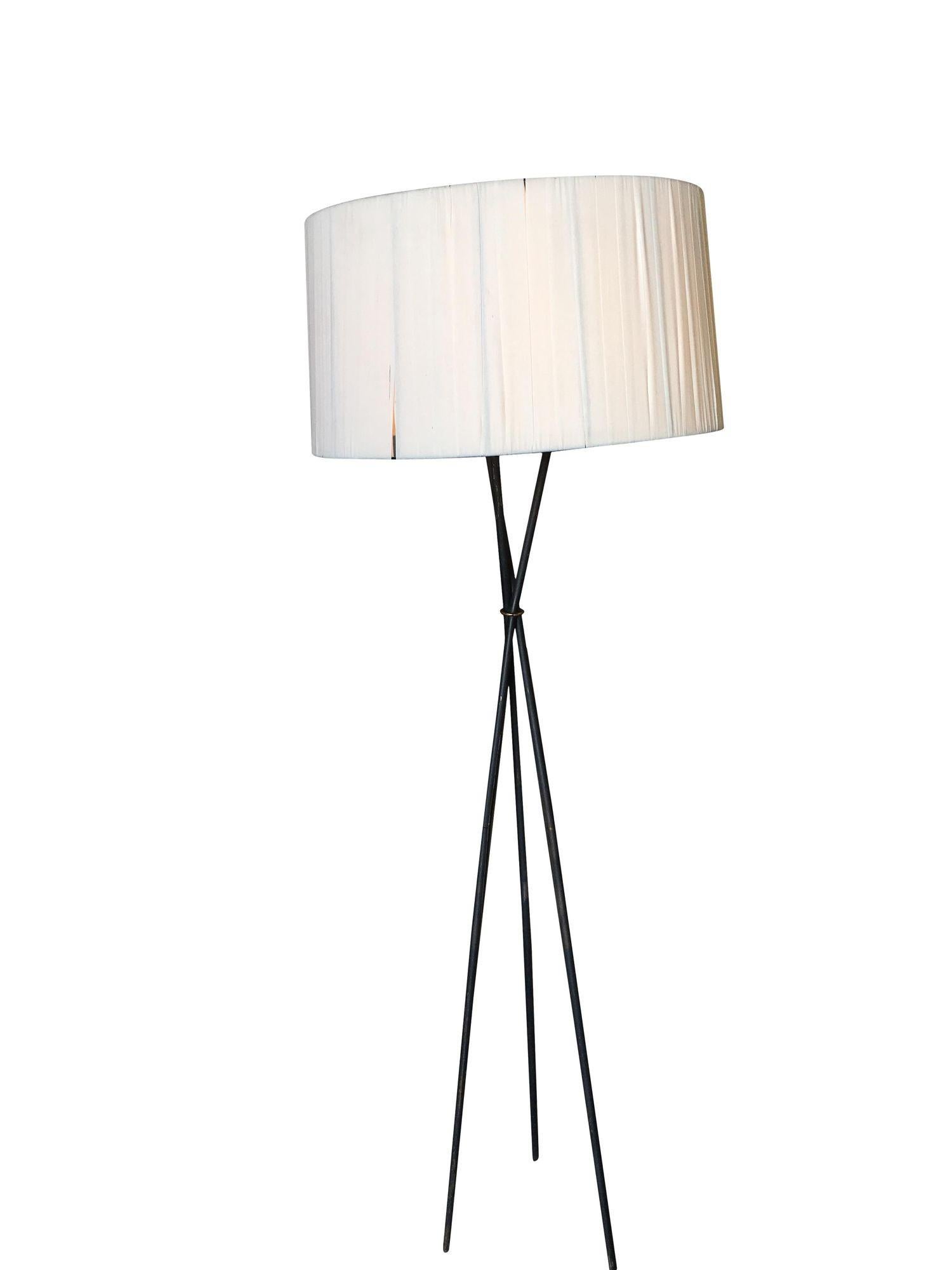Midcentury black iron rod tripod floor lamp with oversized white lamp shade.