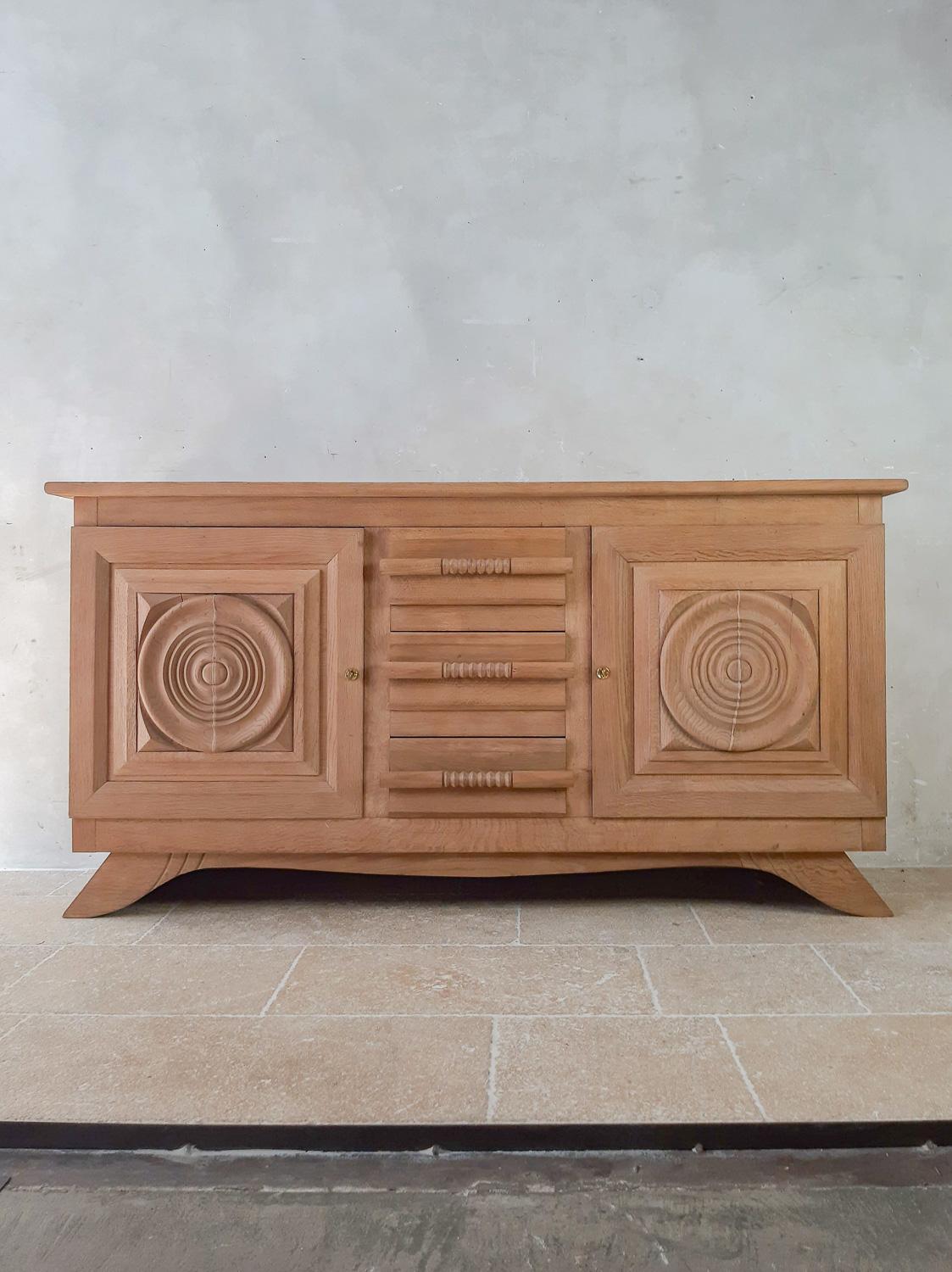 Bleached oak sideboard by Charles Dudouyt from the 1940s, with two round paneled doors and 3 drawers with wooden handles that are incorporated within the design.

Measures: H 99 x W 192 x D 54 cm.

Professionally filled cracks in wood, panels front
