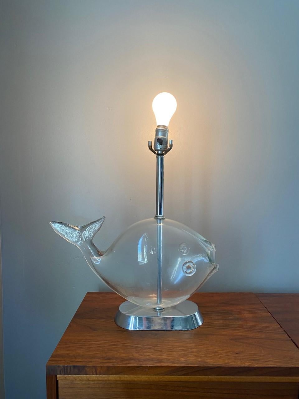 Fischlampe aus Glas von Blenko aus der Mitte des Jahrhunderts, ca. 1960. Die Lampe besteht aus einem mundgeblasenen Fisch aus klarem Glas, der auf einem verchromten Sockel mit einem verchromten Stiel montiert ist.  Die Lampe ist in einem sehr guten