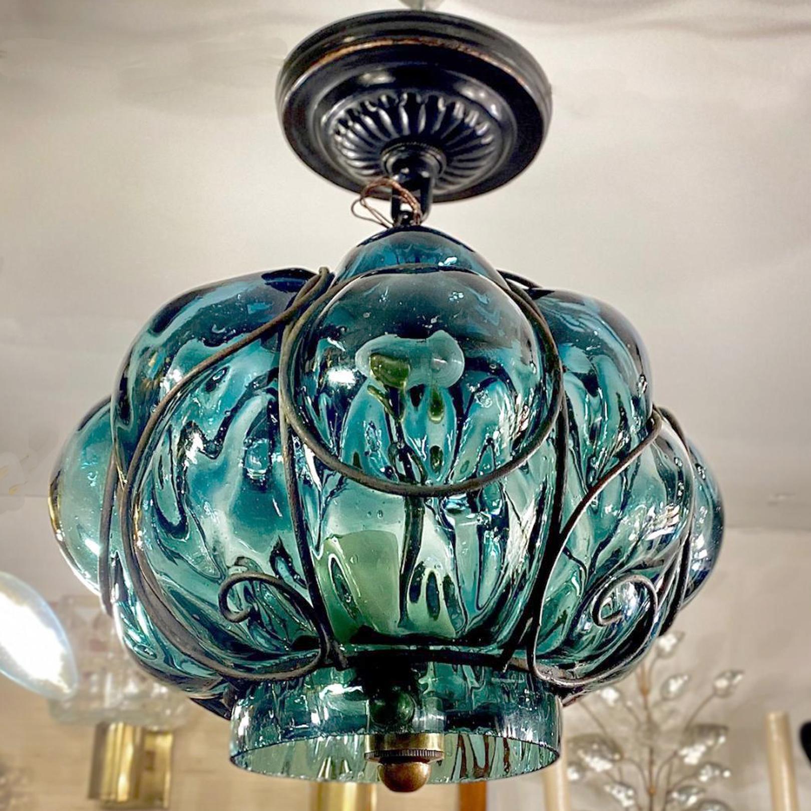 A circa 1950's Italian blown glass lantern with iron work with 2 candelabra lights.

Measurements:
Diameter: 10”
Drop: 12”