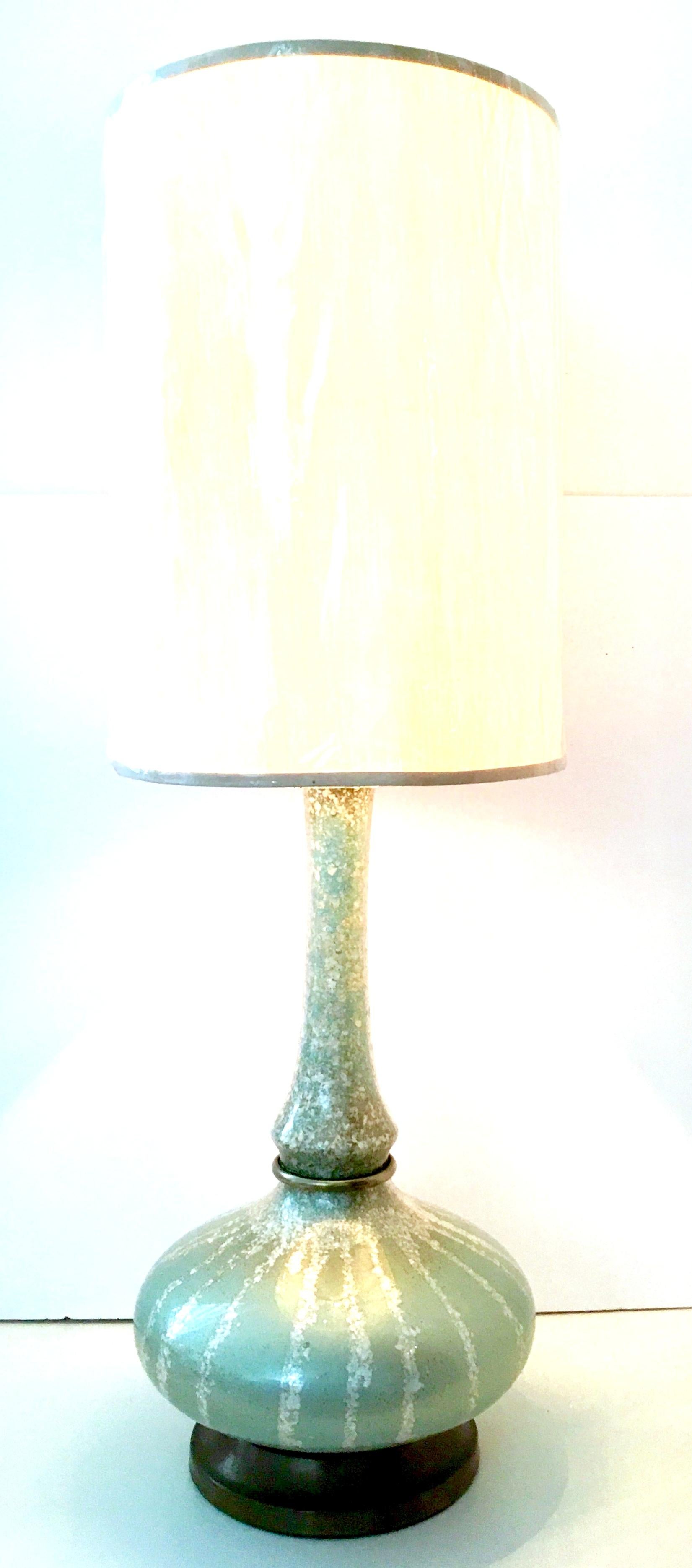 Mid-Century Reverse painted blown art glass and brass lamp. This metallic pistachio green with crushed mother of pearl shell and gold flecks reverse painted lamp features original brass fittings and base. Includes a brass harp and clear Lucite