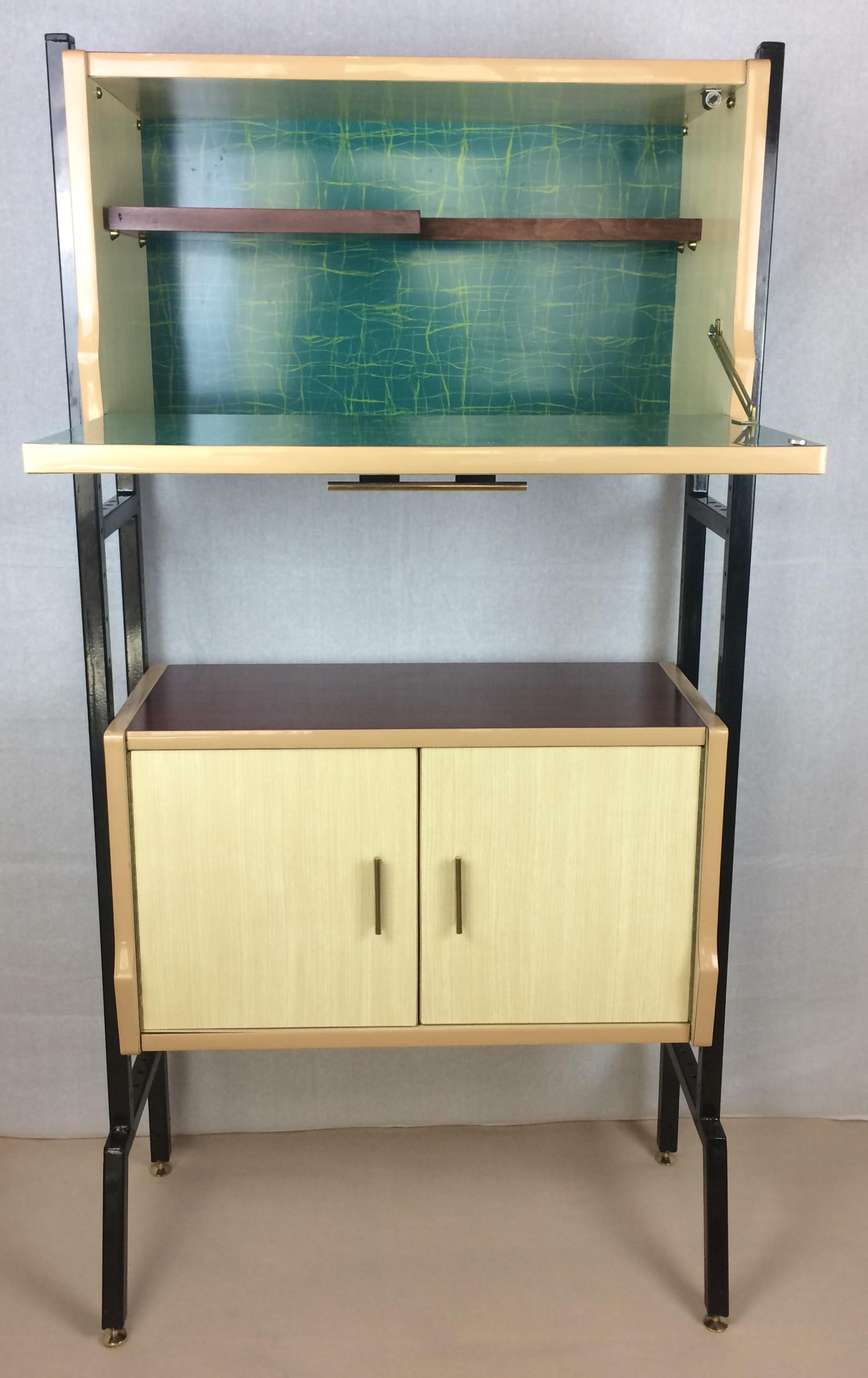 This midcentury cocktail, dry bar cabinet or food pantry features blue, white, ruby red and pale yellow formica sheets, one glass shelf and a back-painted glass top. Stand on sleek, slanted design black metal frame. Would also make a very nice