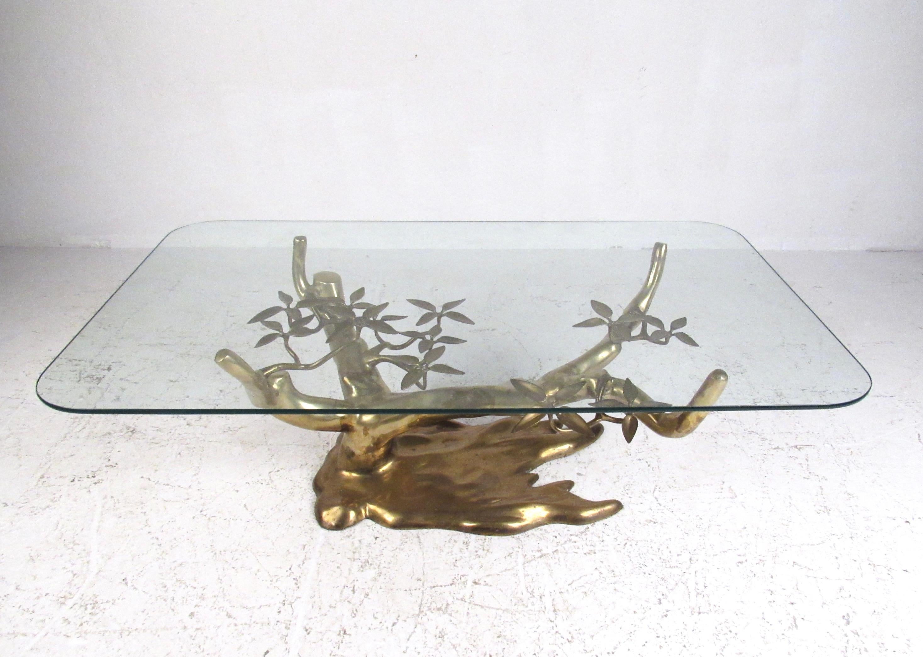 This stunning midcentury cocktail table features a sculptural brass 