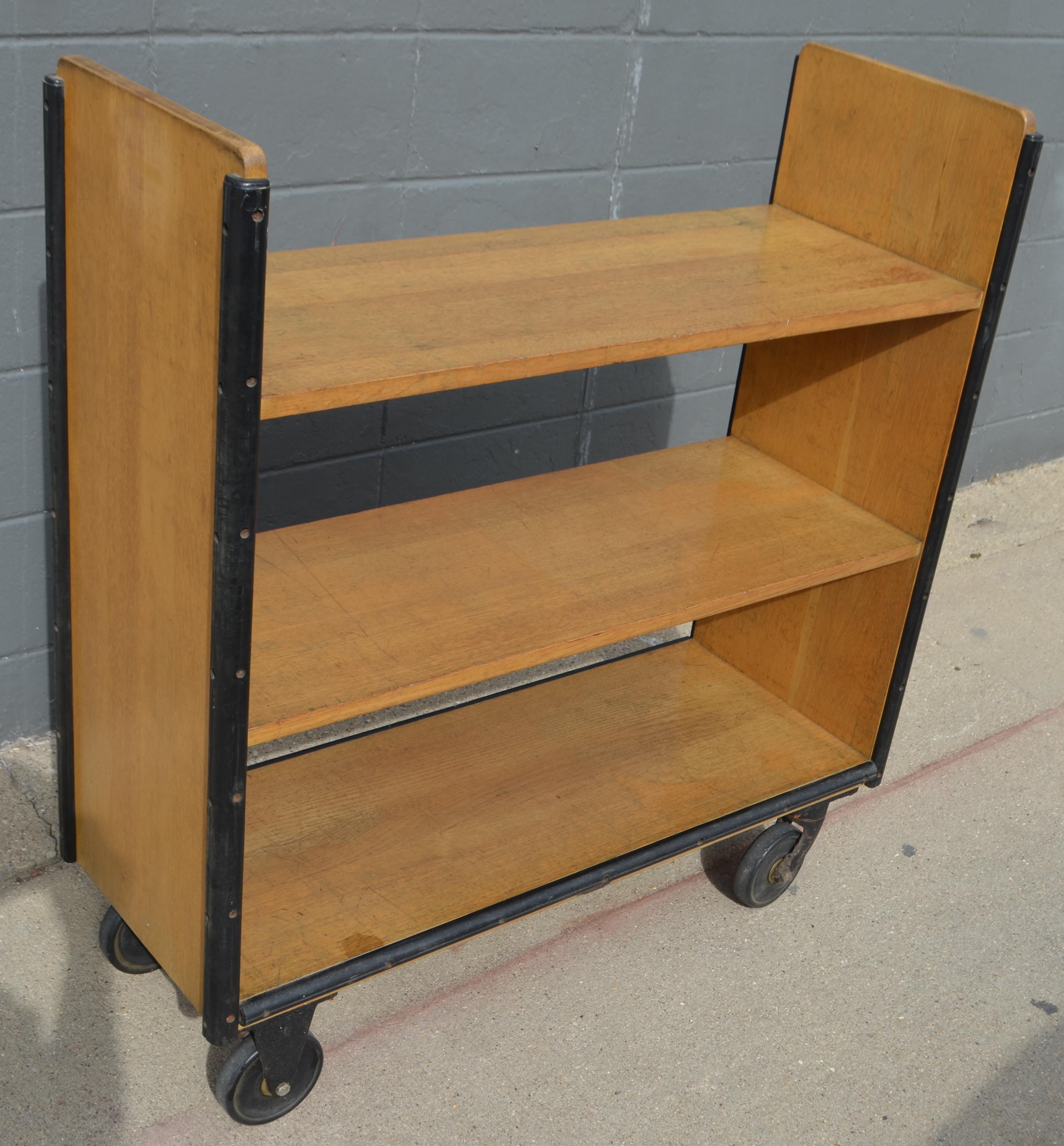 Midcentury book cart of oak on wheels with rubber bumpers. From midwestern public library. Restored, cleaned and sealed. Functions for storage of books, CDs and DVDs. Use it in the bathroom for towels and accessories. Or in the kitchen for cookbooks