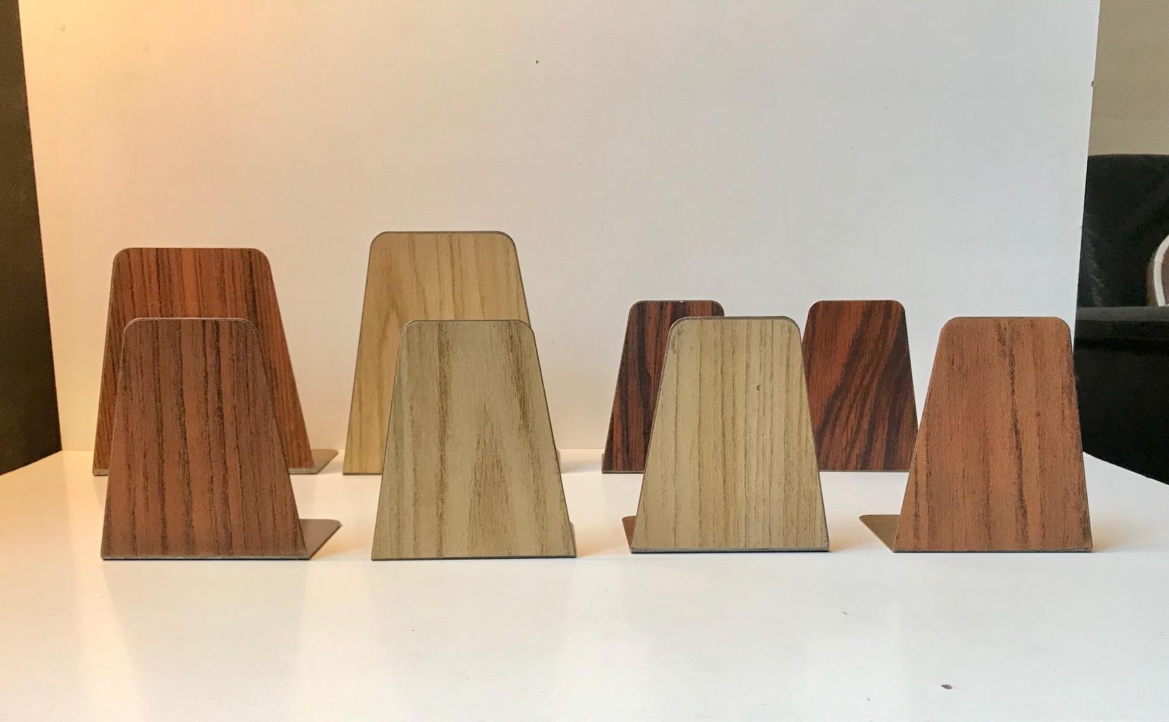A set of 8 enameled steel bookends with applied teak, oak and rosewood superficial veneer/foil. Manufactured in Denmark during the 1960s in a style reminiscent of FM Møbler. Two of them are slightly higher, deeper and wider than the 6 regular ones.