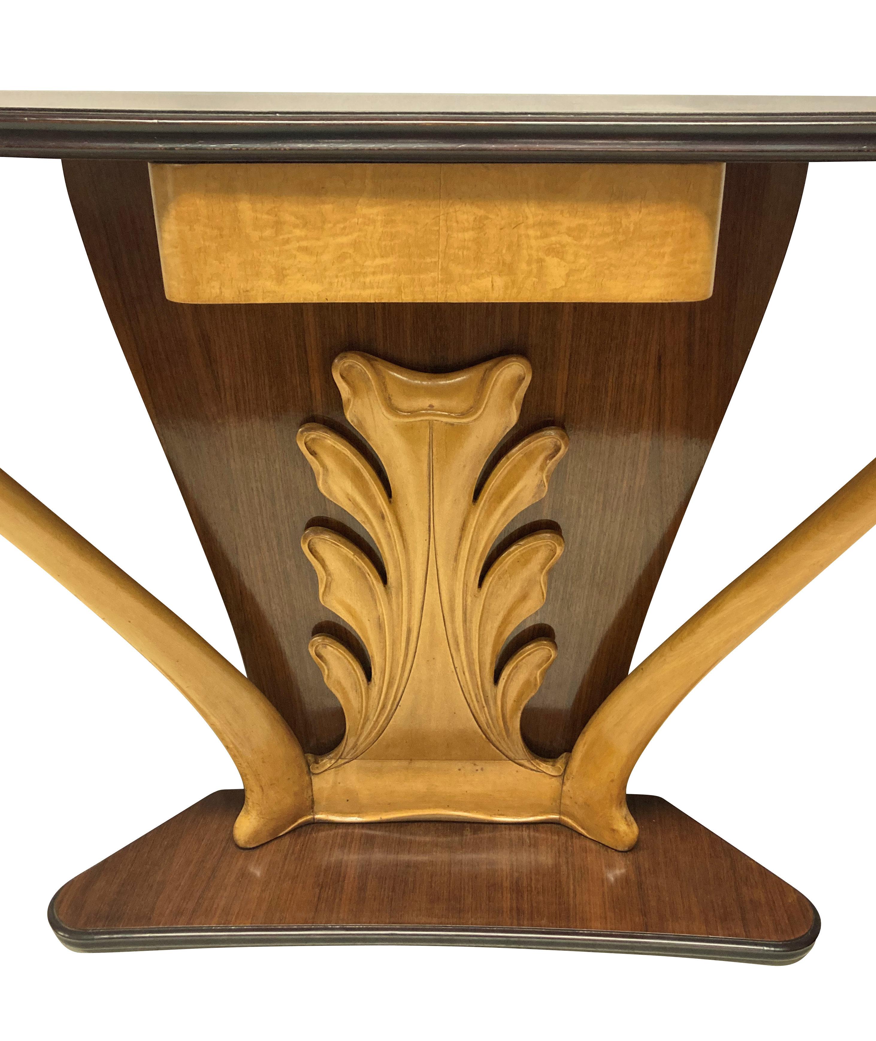 A stylish console table by Borsani of organic form, in walnut, sapele andfruitwood. With a serpentine base and top, the central design, beautifullycarved in a florid manner with a central drawer.