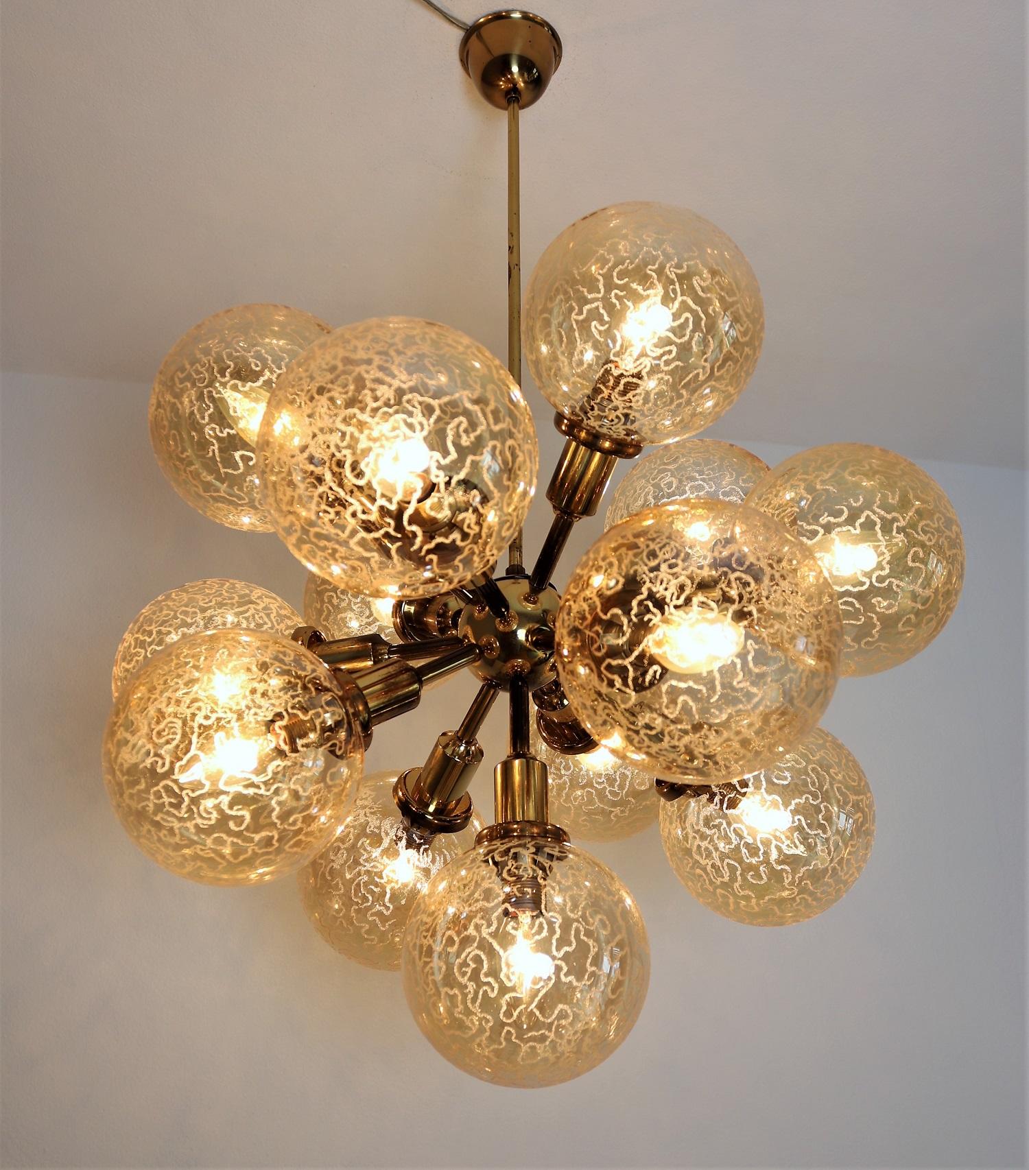 Beautiful Sputnik chandelier with shiny golden brass frame and gorgeous 13 glass spheres.
Made in Germany by Kaiser Leuchten during the 1970s.
The glasses are in amber or honey color with bizarre pattern. The diameter of one glass sphere is 5.9in or