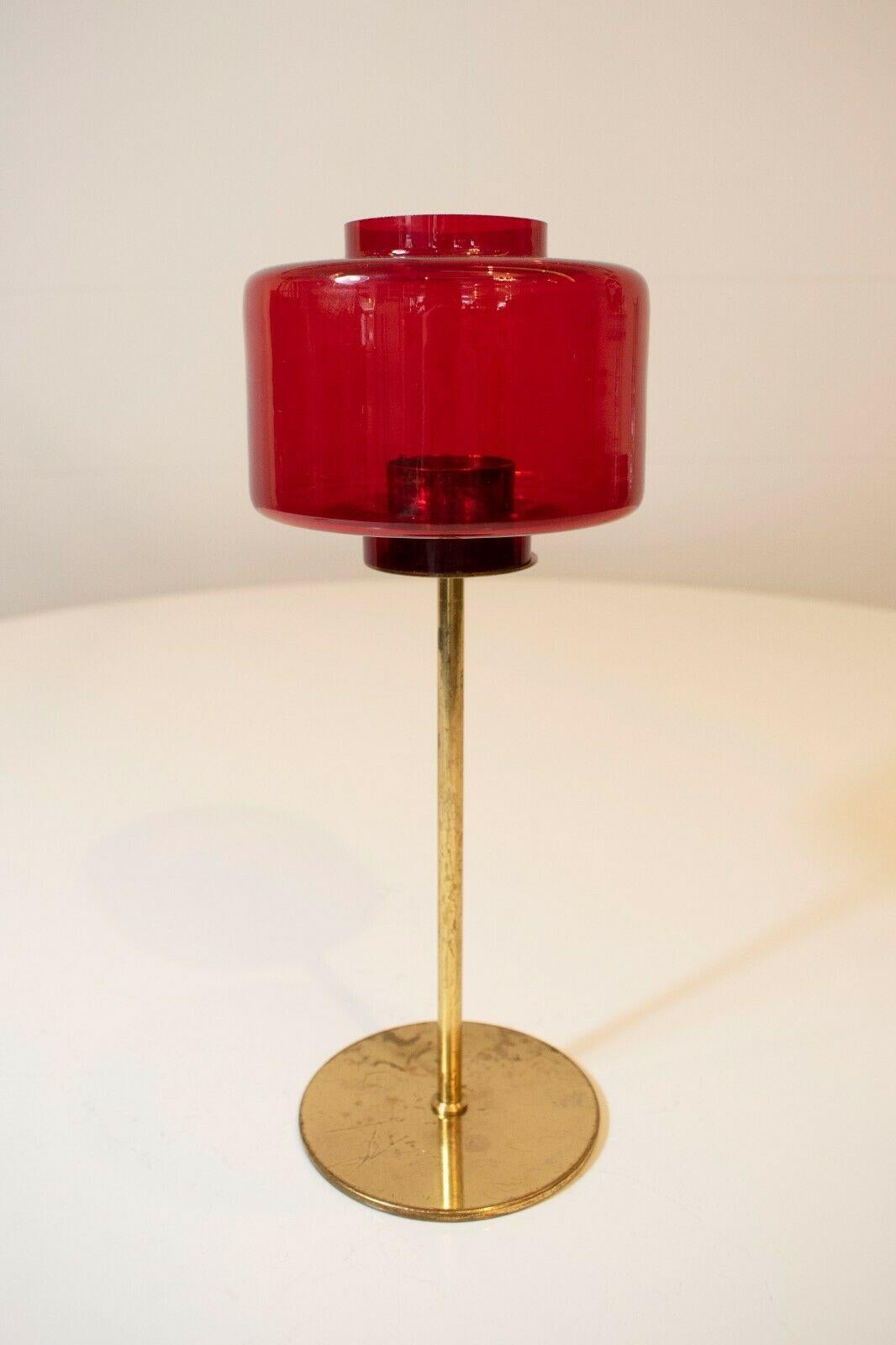This rare and collectable candleholder was made in Sweden, 1960's and designed by Hans-agne Jakobsson. 

A square red top set upon an elegant brass base, this piece sports its original and authentic patina. It shows signs of usage expected with it's