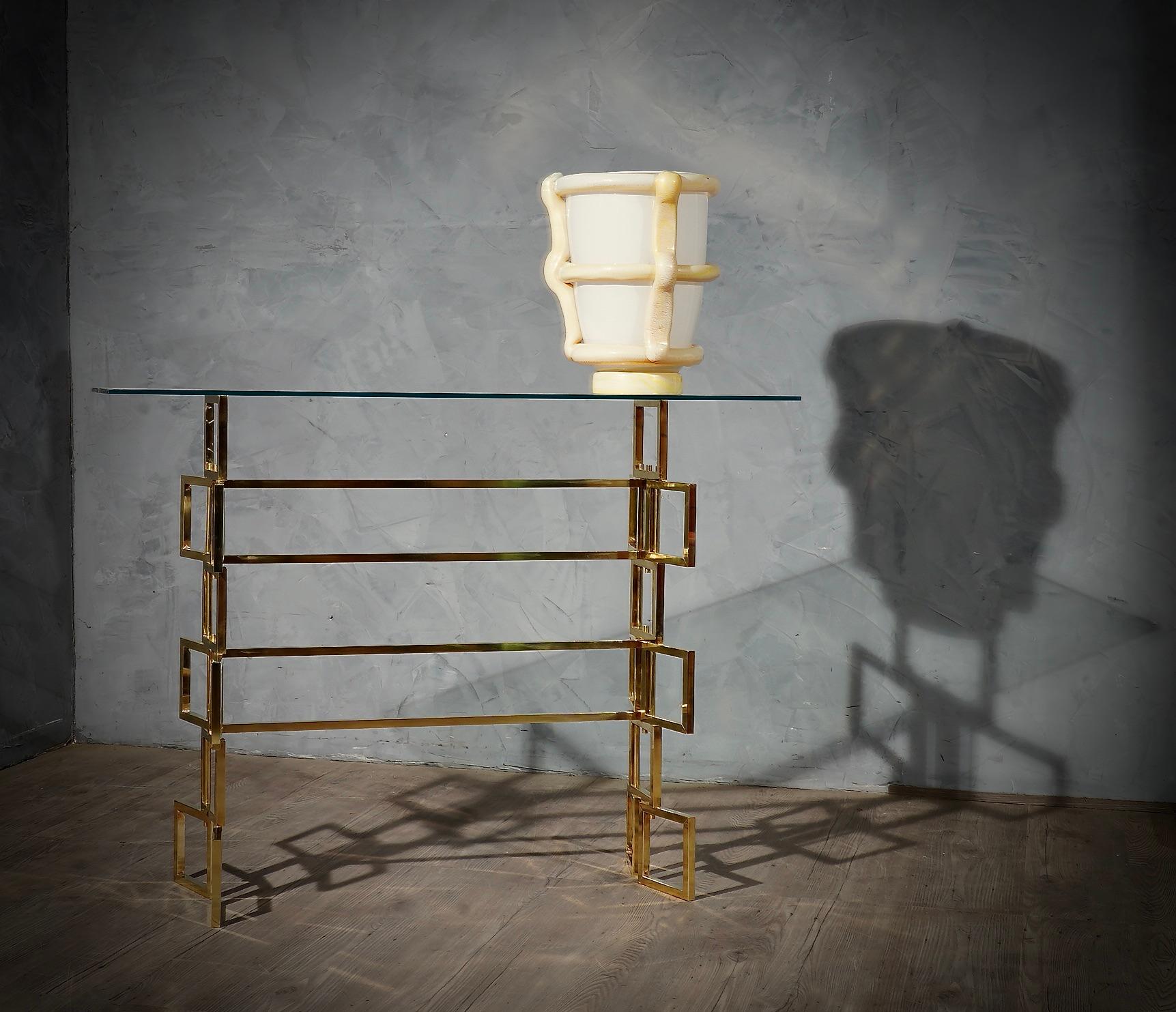 Console with a very particular shape, very original design also due to the use of precious materials such as brass. Minimalist structure, due to the glass top.

The console is composed of a structure of squares in brass tube. The squares are of one