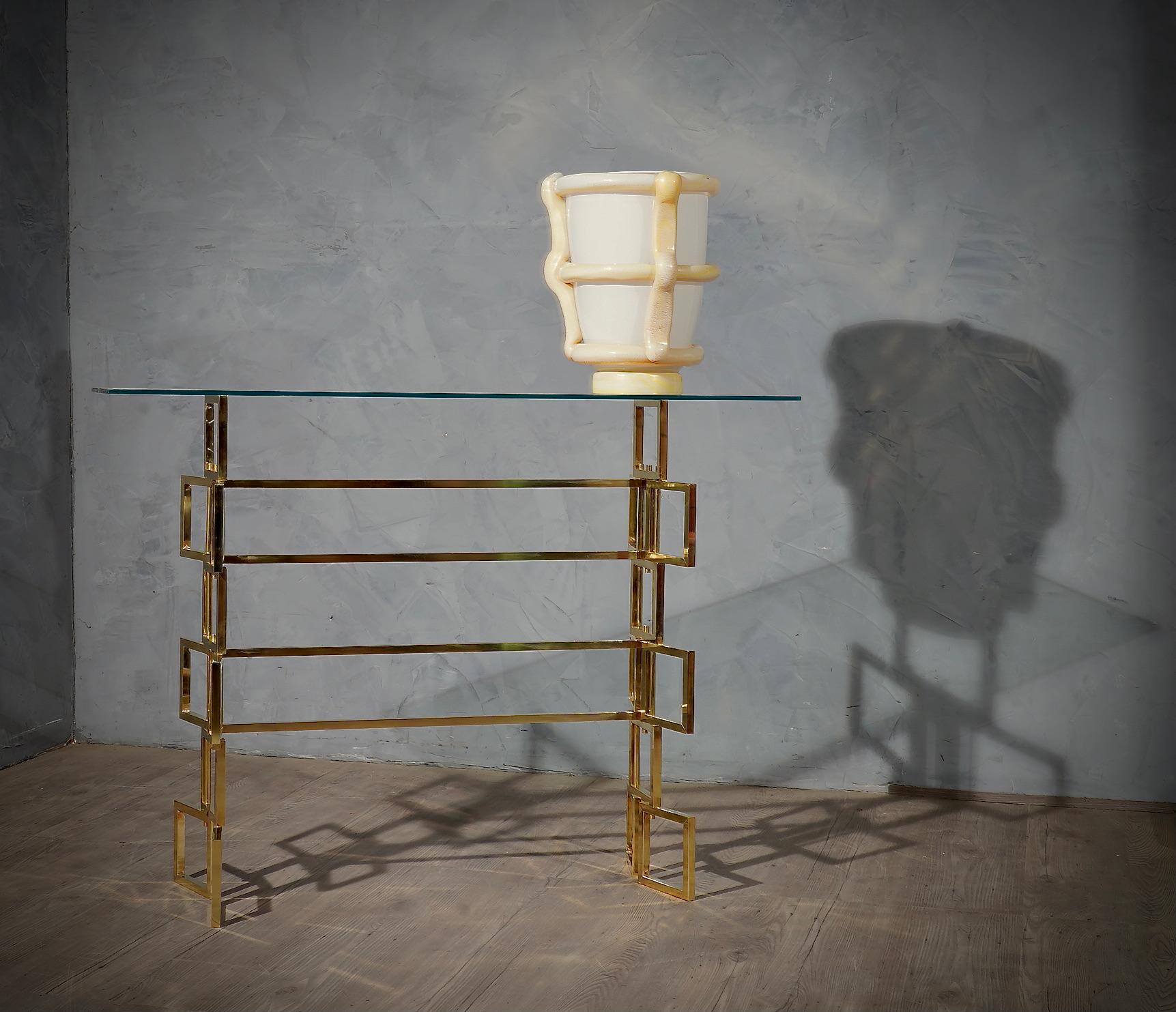 Console with a very particular shape, very original design also due to the use of precious materials such as brass. Minimalist structure, due to the glass top.

The console is composed of a structure of squares in brass tube. The squares are of one