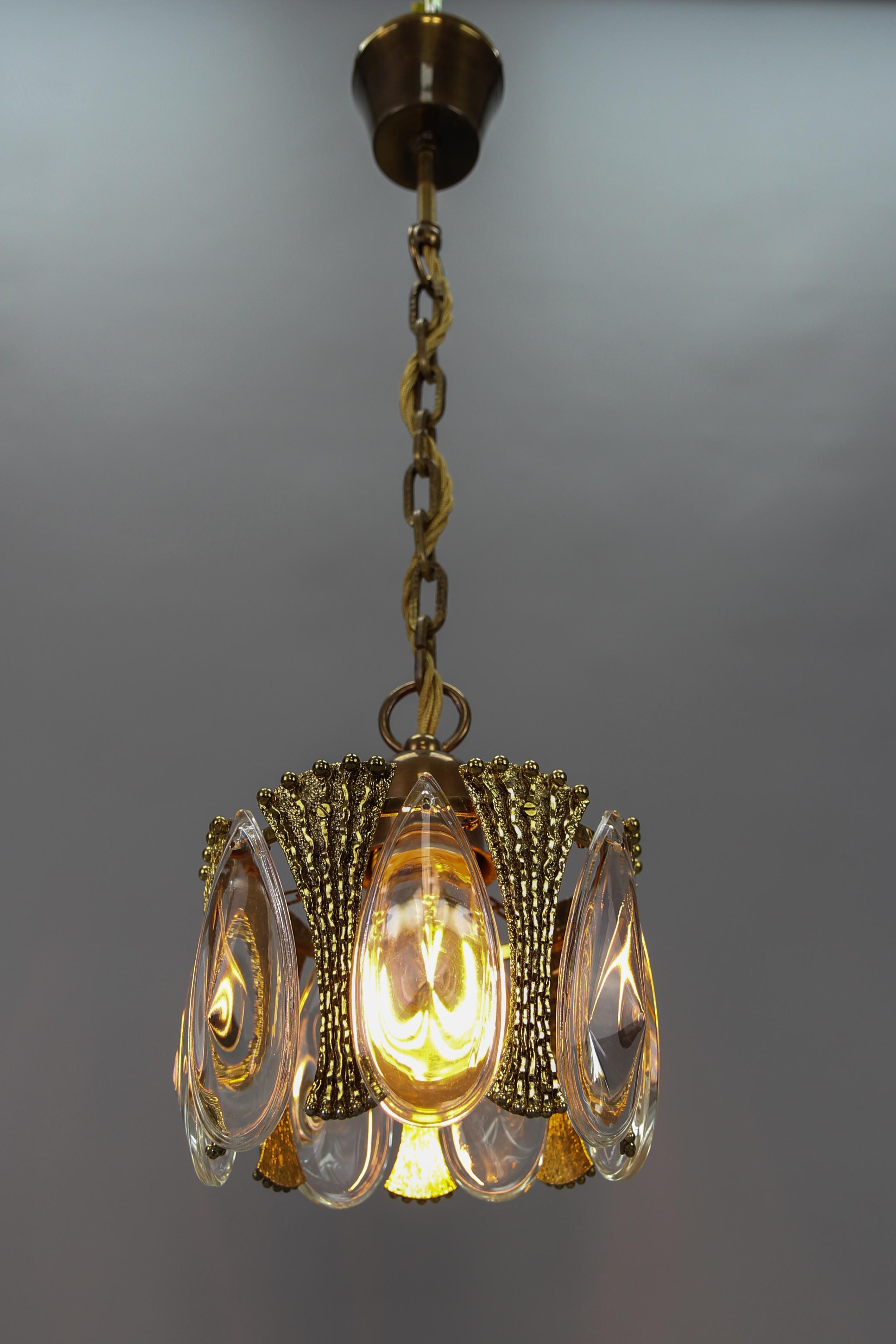 Midcentury single-light brass and glass pendant light fixture, Germany, circa the 1970s.
An adorable and compact pendant light fixture decorated with beautiful brass details and oval teardrop-shaped glass pendants.
One socket for E27 (E26) size