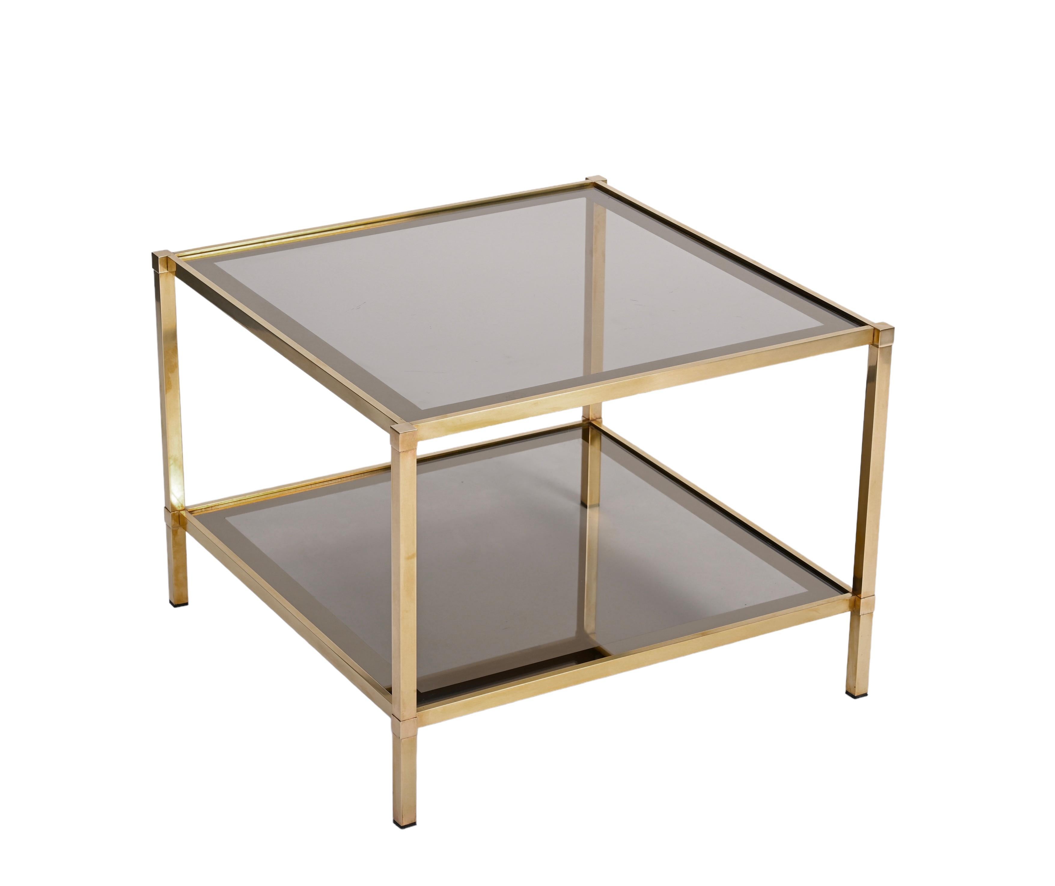 Amazing small mid-century brass and smoked bronzed glass square coffee table with mirrored frame on two levels with wheels. This fantastic item was produced in Italy during the 1970s, and it is attributed to Maison Jansen. 

The straight lines of