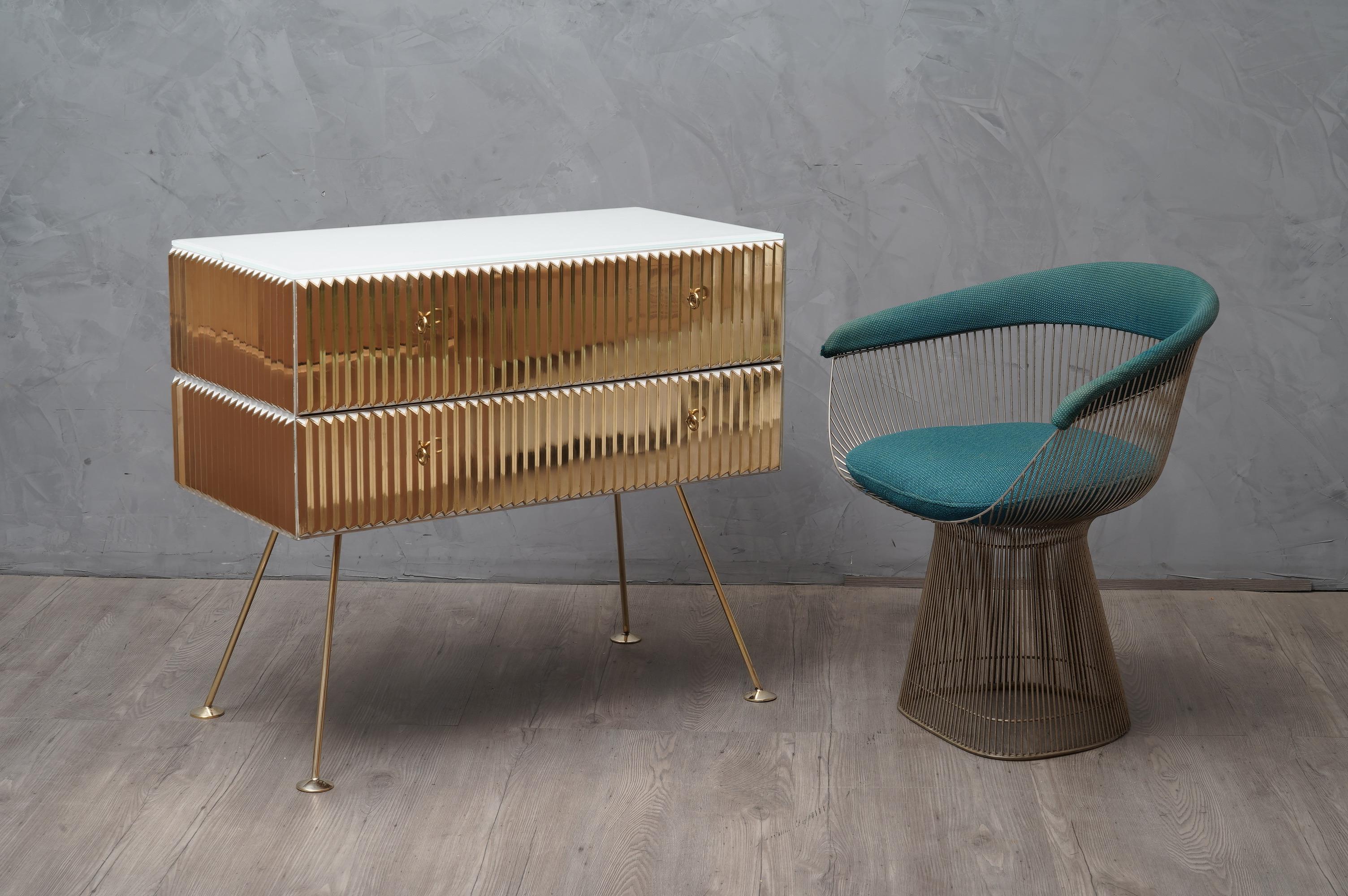Thrilling and elegant vintage chest of drawers, designed with precious materials such as brass and glass. Unique and original object of its kind.

The dresser consists of a wooden body with two drawers, on which triangular shaped brass profiles