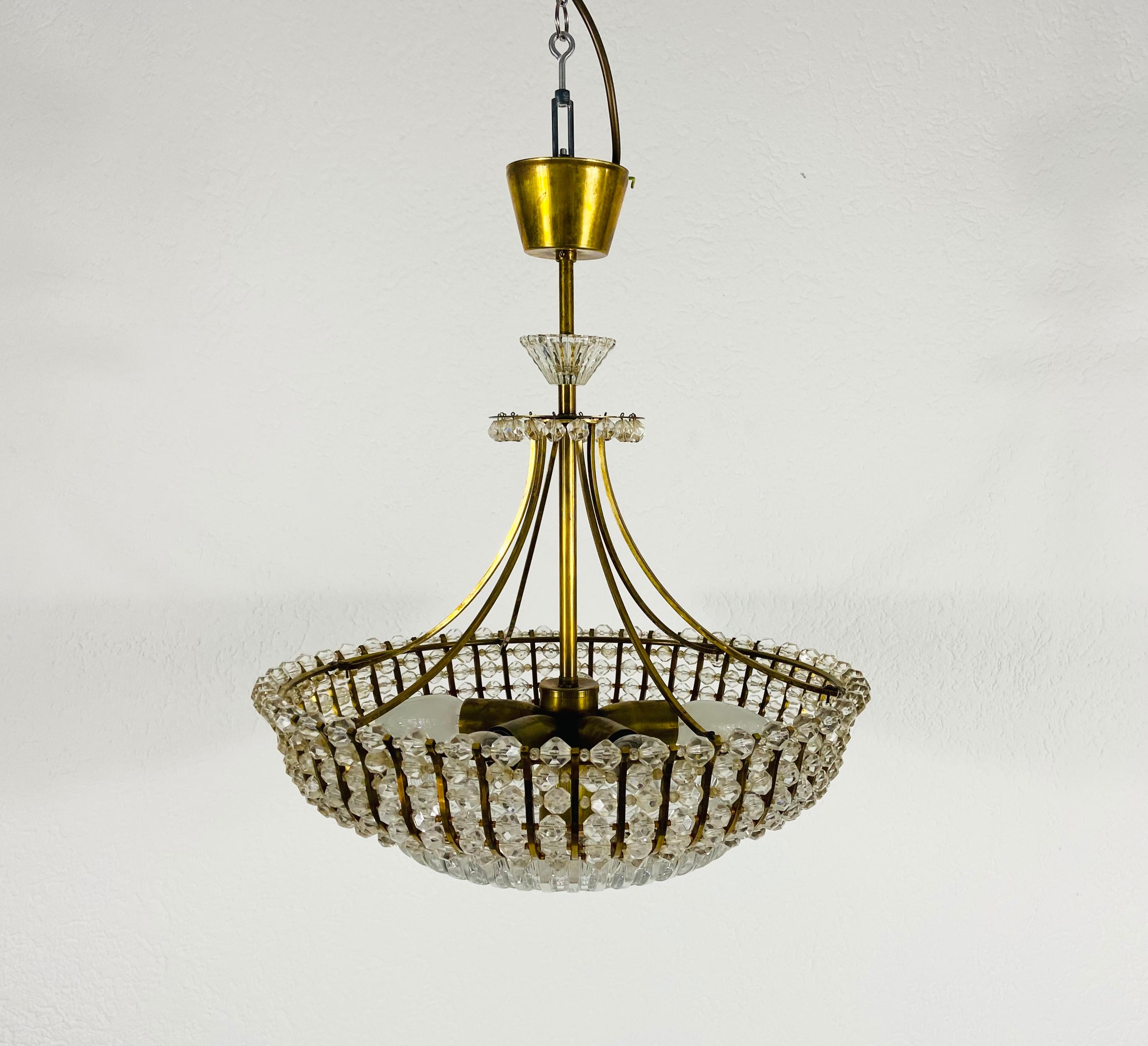 A brass chandelier made by Rupert Nikoll, Austria in the 1960s. The lighting has an amazing midcentury design. It is made of brass and small glasses and fits perfectly into a living room. The fixture has a very nice Hollywood Regency floral