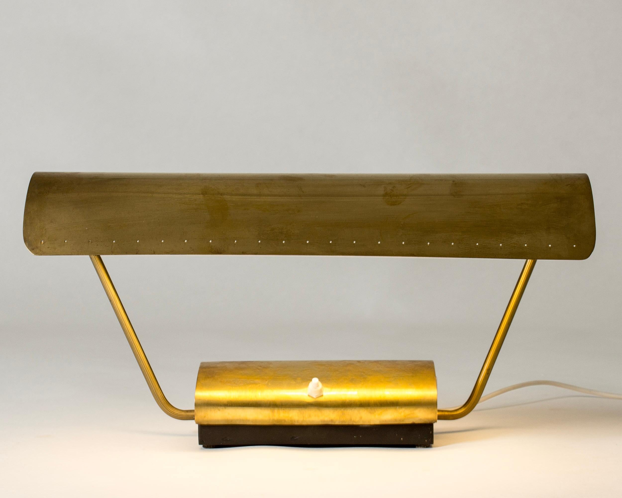 Cool midcentury desk lamp from Philips, made from brass in a wide design. Adjustable lamp shade with decorative perforated holes. Flourescent tube light source.