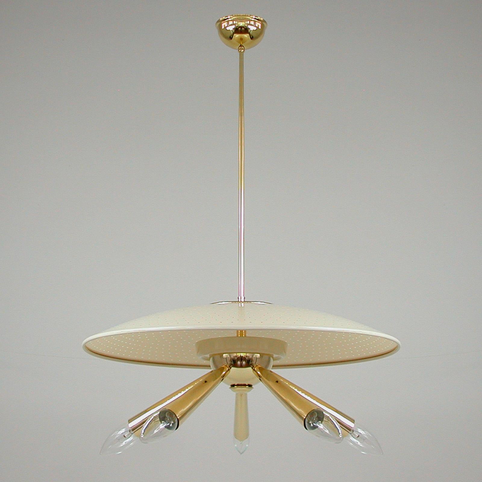 This unusual chandelier was designed and manufactured in Italy in the 1950s. It features a brass body with 5 brass lamp arms and cream colored perforated plastic dome lamp shade. Wired for use in US and any other country of the world. 

The light