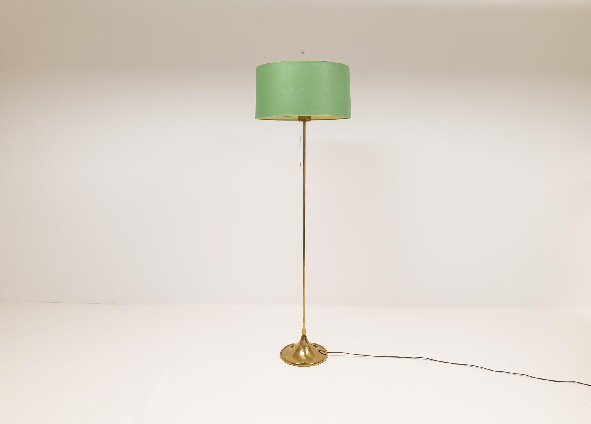 Wonderfully designed floor lamp from Bergboms Sweden. Made in brass and cast iron. They were made in the 1960 and have a nice, shaped trumpet foot. This one with the original green shade with acrylic top to give that special light.

Good working