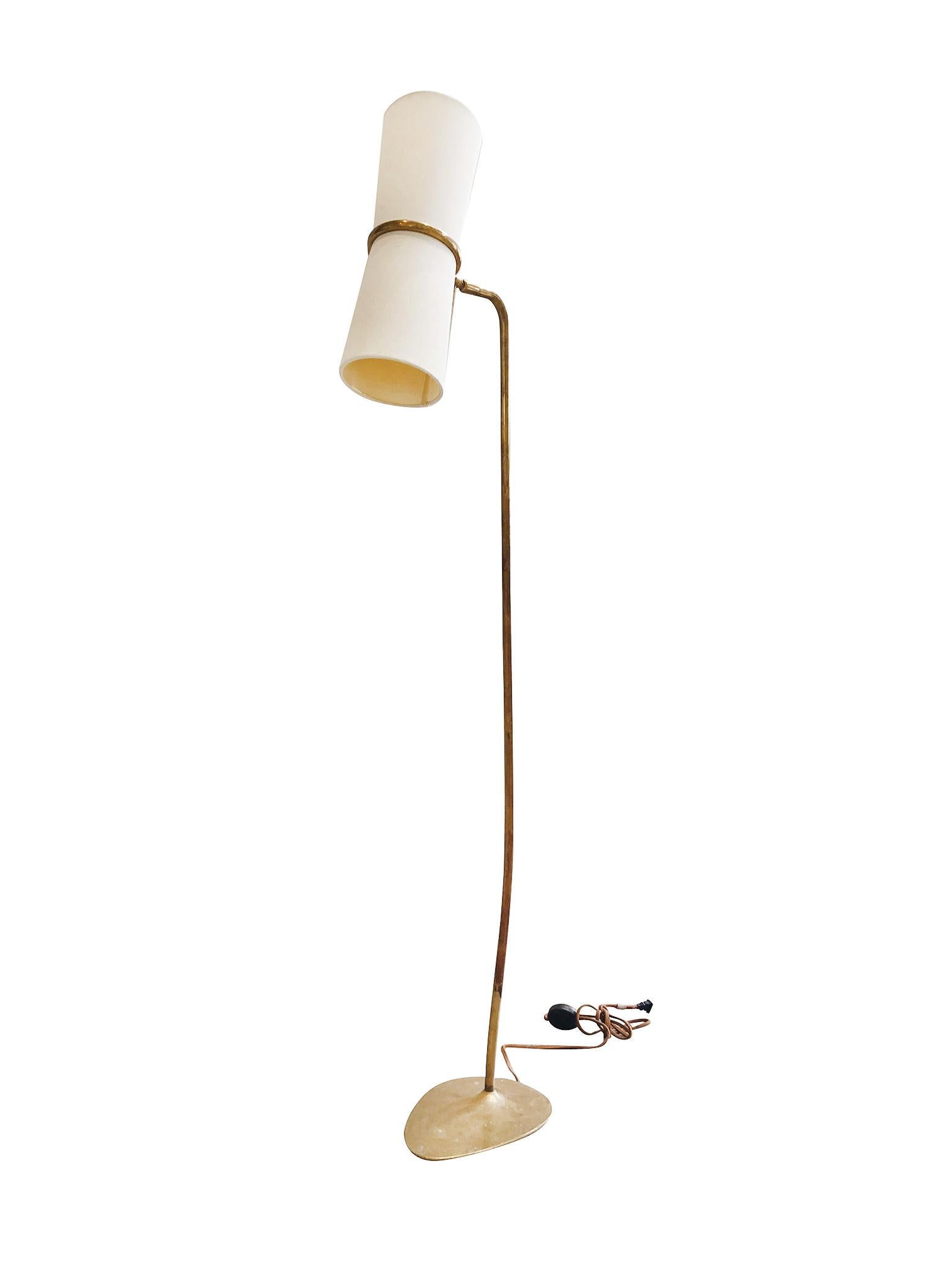 Midcentury Modern brass floor lamp with a long stem-like body and a flat oval-shaped base. The double-head consists of a top and bottom socket. A small white linen shade fits over each socket. The lamp is newly rewired.

Dimensions:
58 in.