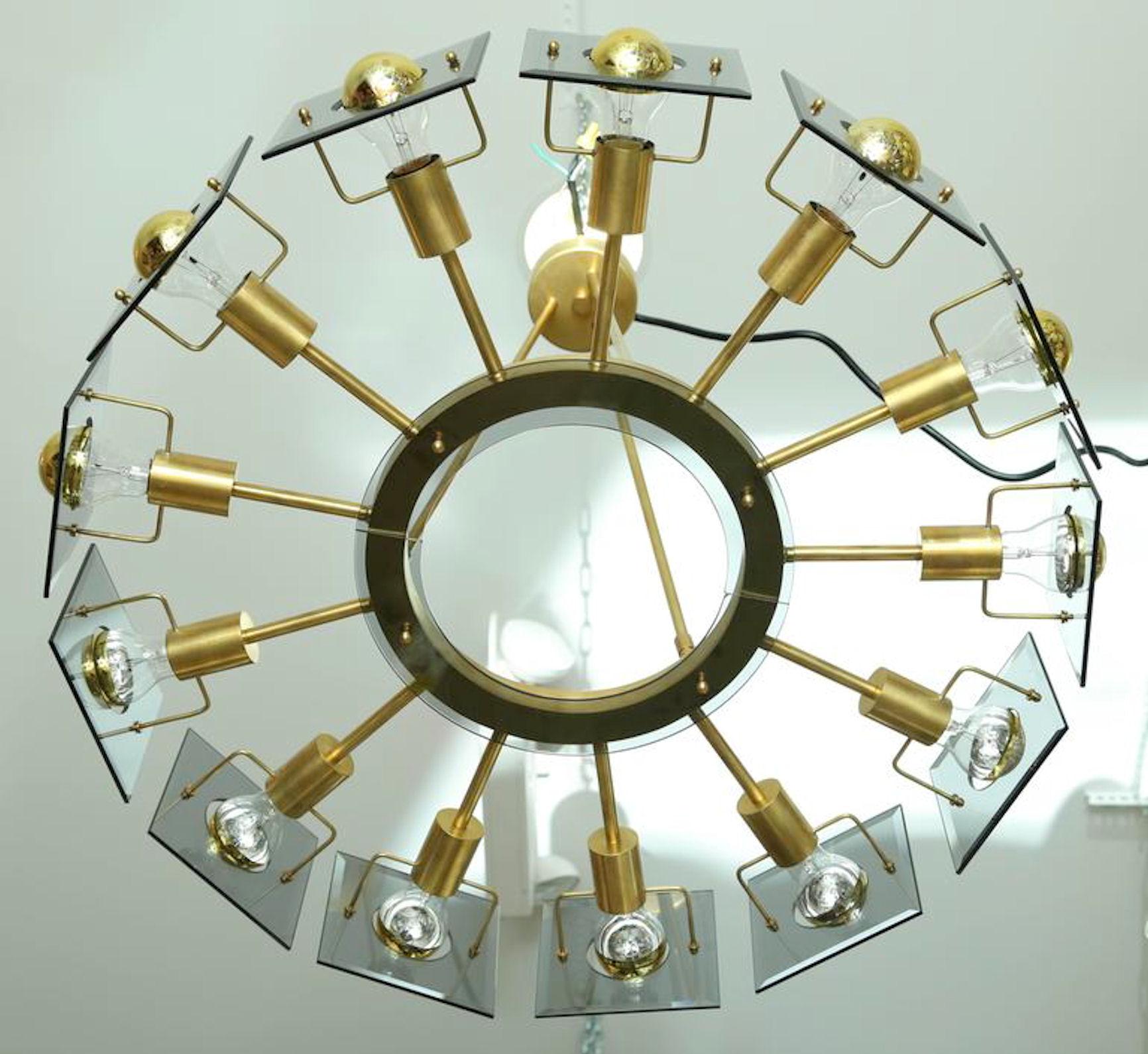 Wheel shaped, 13 lights brass and smoked square bevelled glass,
Mid-Century Modern, Italian chandelier, design by Gino Paroldo, probably edited by Fontana Arte,
circa 1970s.
Rewired.