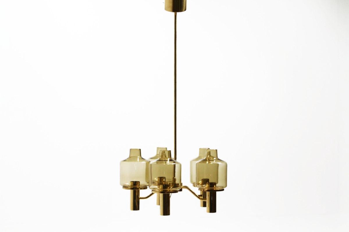 Trendy Scandinavian style and high quality manufacturing for this midcentury chandelier. These five-light brass chandelier was created by Swedish designer Hans-Agne Jakobsson for Markaryd back in the 1960s. The smoking glasses add a sense of mystery