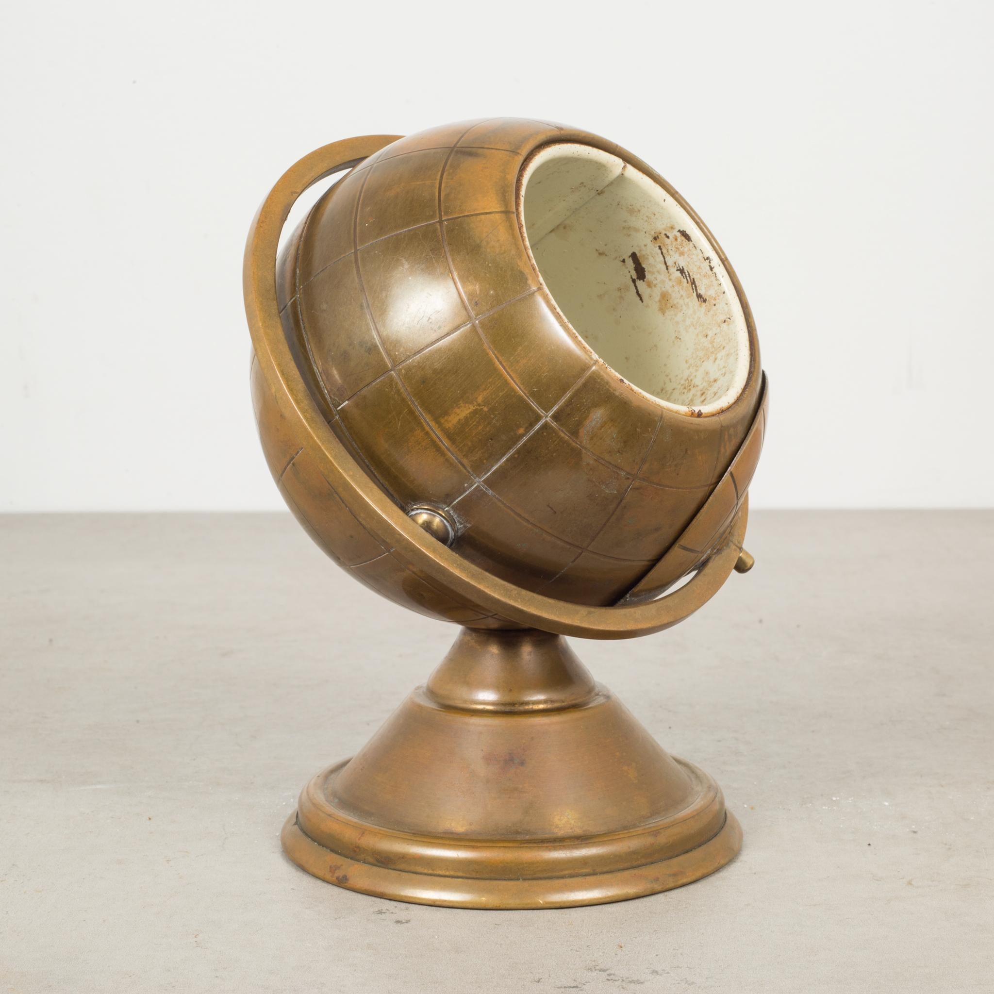 About 

This is an original midcentury brass cigarette holder. The lid slides open on the globe's axis to reveal a metal interior designed to hold cigarettes. This globe is unique because it has a leather nameplate on the bottom. This piece has
