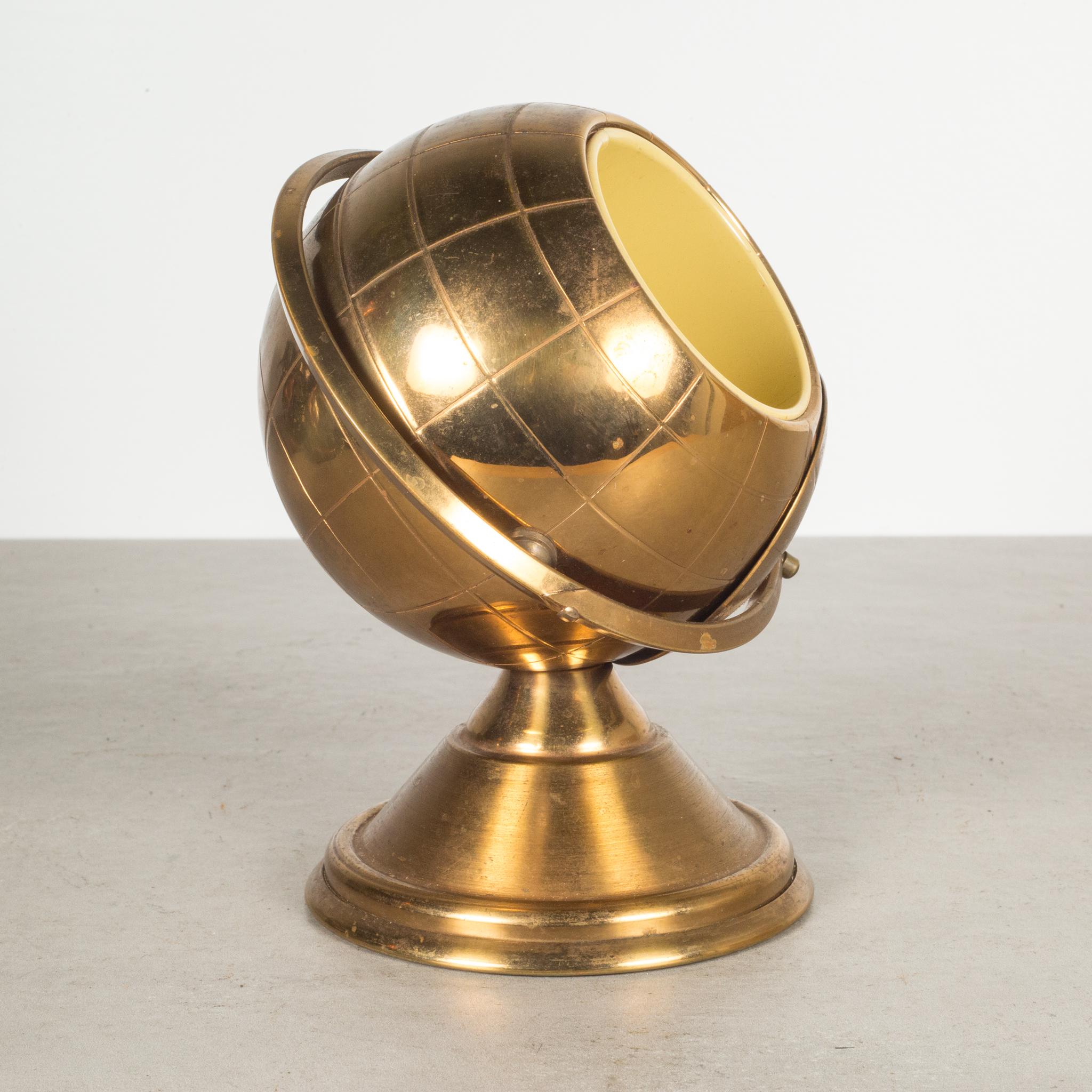 About 

This is an original midcentury brass cigarette holder. The lid slides open on the globe's axis to reveal a metal interior designed to hold cigarettes. This globe is unique because it has a leather nameplate on the bottom. This piece has