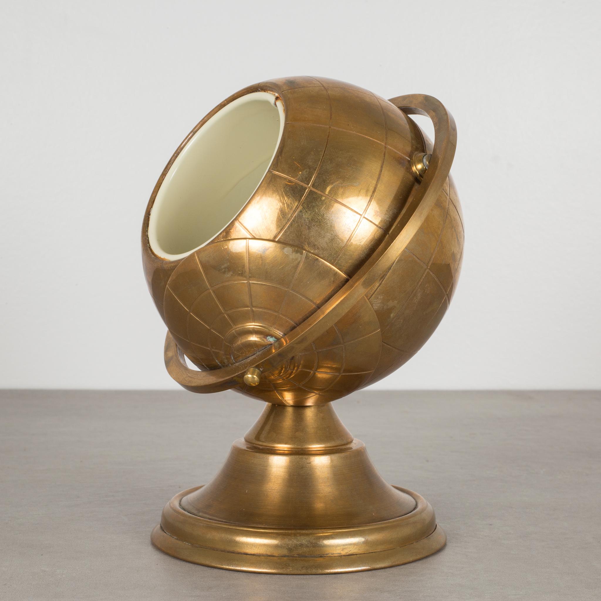 Modernist brass globe cigarette holder with metal interior and swing arm lid.